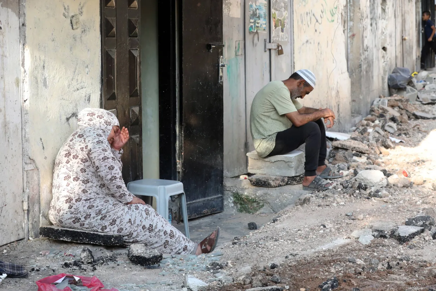 فلسطينيان يجلسان خارج منزلهما في مخيم جنين الجمعة (إ.ب.أ)