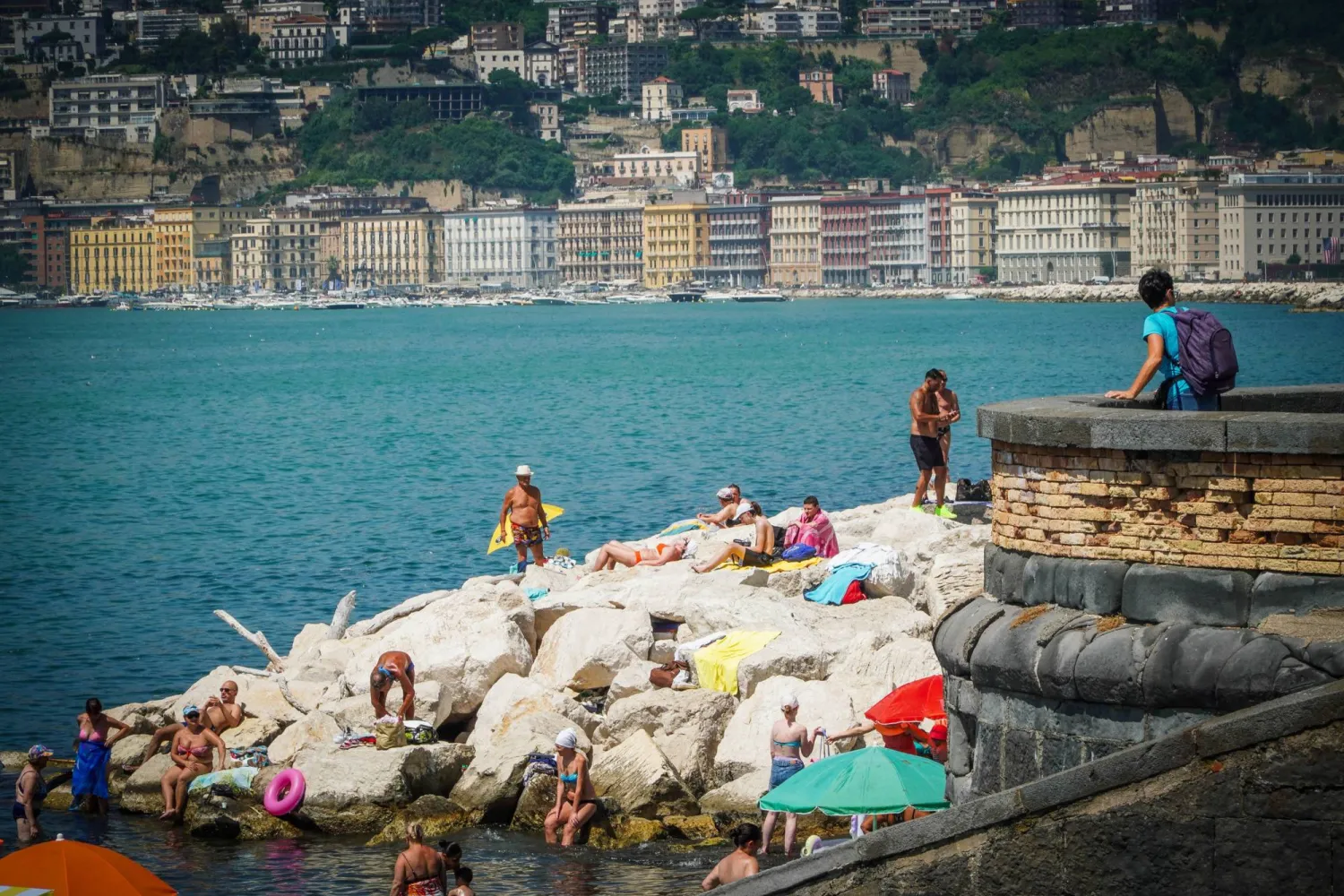يقضي الناس وقتاً على الشاطئ خلال يوم حار في نابولي (إ.ب.أ)
