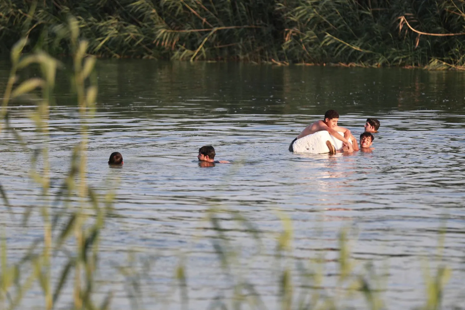 فتيان يسبحون في نهر بقرية البو مصطفى قرب الحلة حيث تجاوزت درجات الحرارة 45 درجة مئوية (أ.ف.ب)