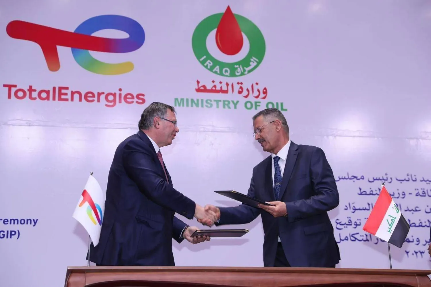 وزير النفط العراقي وممثل «توتال» يتبادلان الوثائق بعد توقيع الاتفاقية (الشرق الأوسط)