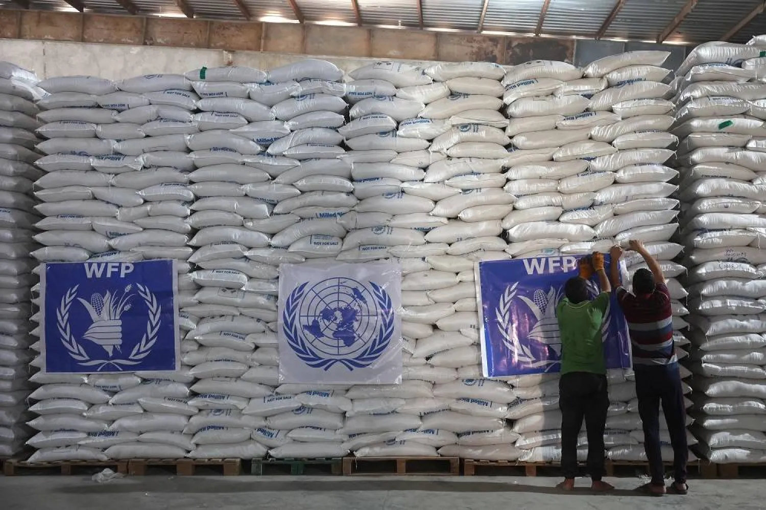 Workers unload bags of aid at a warehouse near the Syrian Bab al-Hawa border crossing with Türkiye, on July 10, 2023. (AFP) 