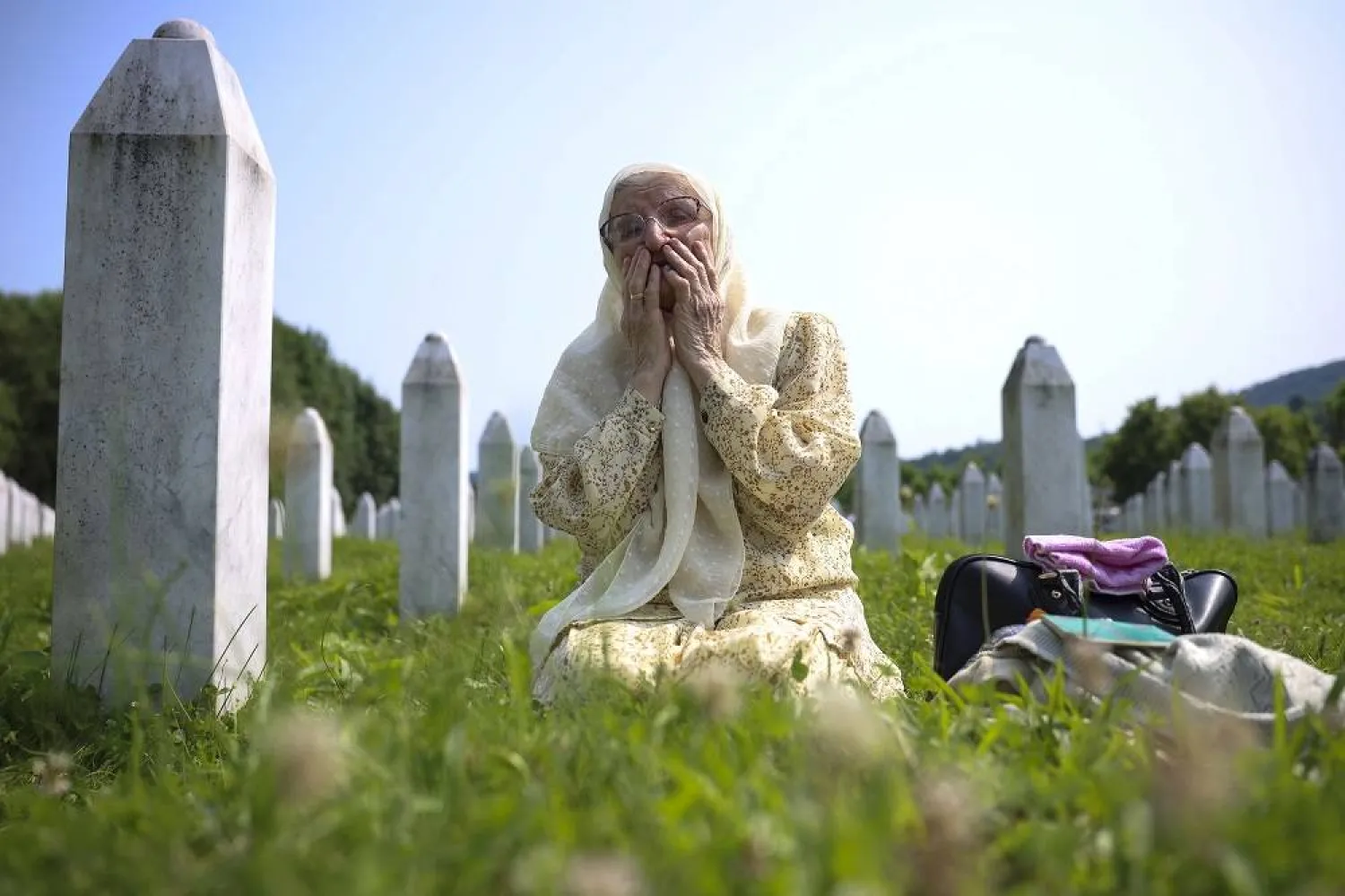 A Bosnian Muslim woman mourns next to the grave of her relative, victim of the Srebrenica genocide, in Memorial Centre in Potocari, Bosnia, Tuesday, July 11, 2023. (AP)