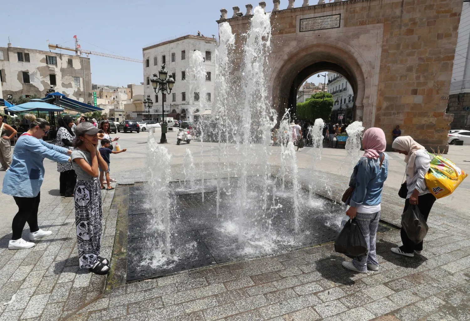 أشخاص يبردون أجسادهم قرب نافورة باب البحر بالعاصمة التونسية (إ.ب.أ)