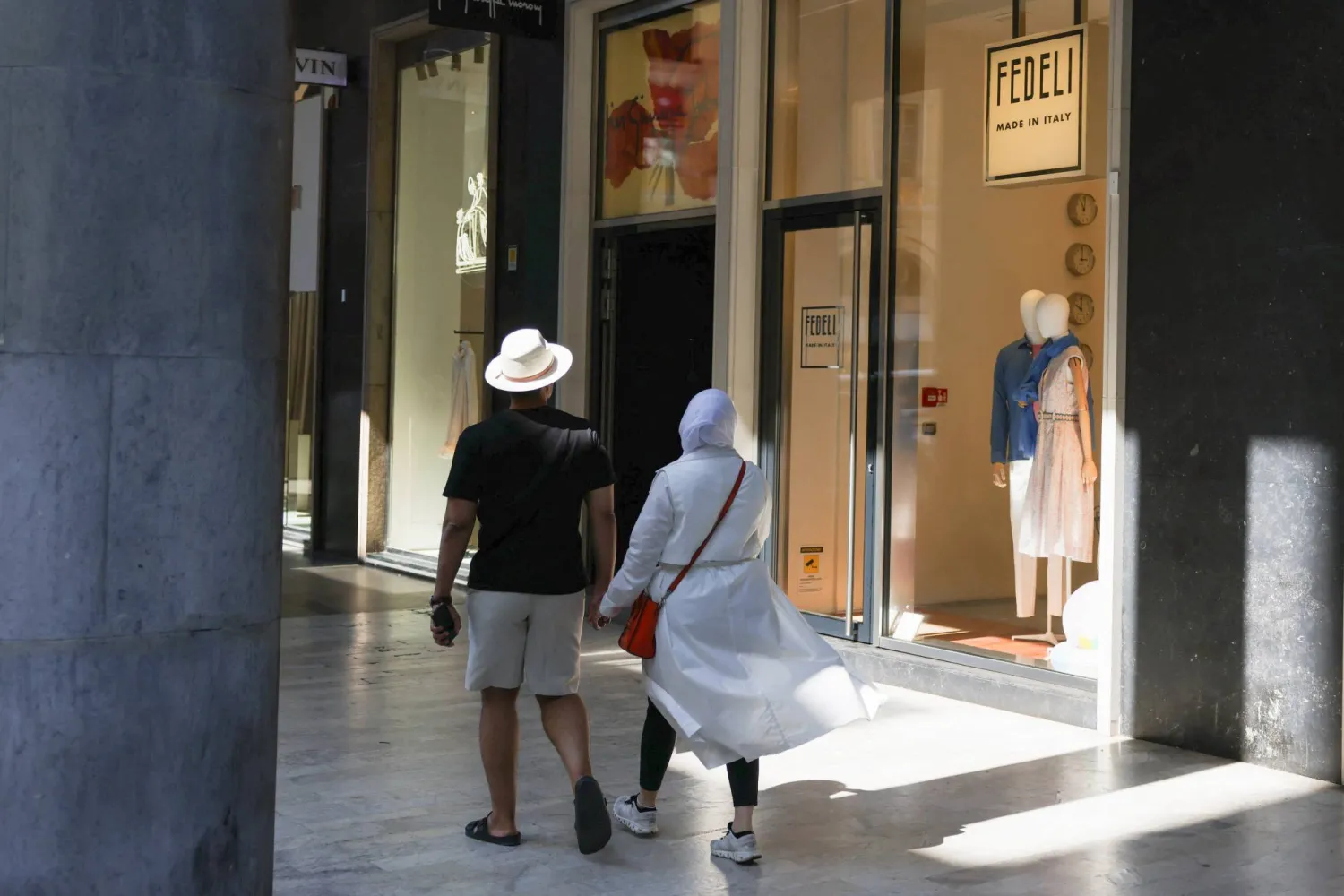 A couple walks by an Italian knitwear brand Fedeli shop in Milan, Italy, June 23, 2023. REUTERS/Claudia Greco