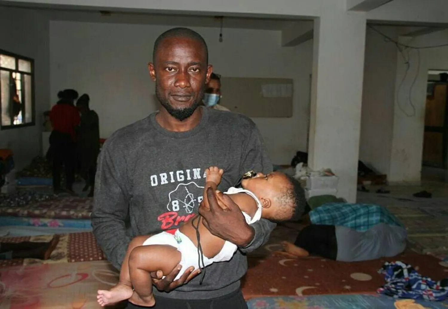 أحد المهاجرين غير النظاميين يحمل رضيعه بعدما تم إنقاذهما مع آخرين من قبل سلطات طرابلس (وزارة الداخلية بحكومة «الوحدة»)