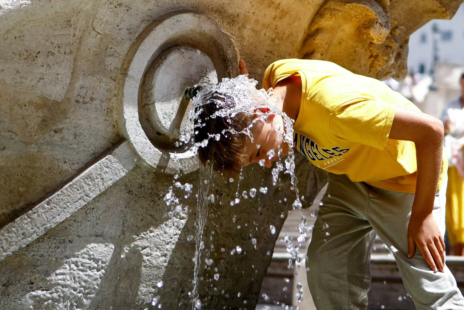 FILE PHOTO: A boy cools off at Fontana della Barcaccia at the Spanish Steps during a heat wave across Italy as temperatures are expected to rise further in the coming days, in Rome, Italy July 17, 2023. REUTERS/Guglielmo Mangiapane