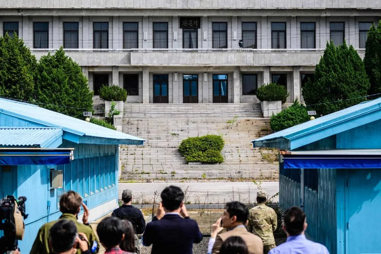Members of the media (foreground) take photos beyond an UNC (United Nations Command) soldier (center R) and a South Korean soldier (center L) as they stand guard before North Korea's Panmon Hall (rear C) and the military demarcation line separating North and South Korea, at the Joint Security Area (JSA) of the Demilitarized Zone (DMZ) in the truce village of Panmunjom on October 4, 2022. (AFP)