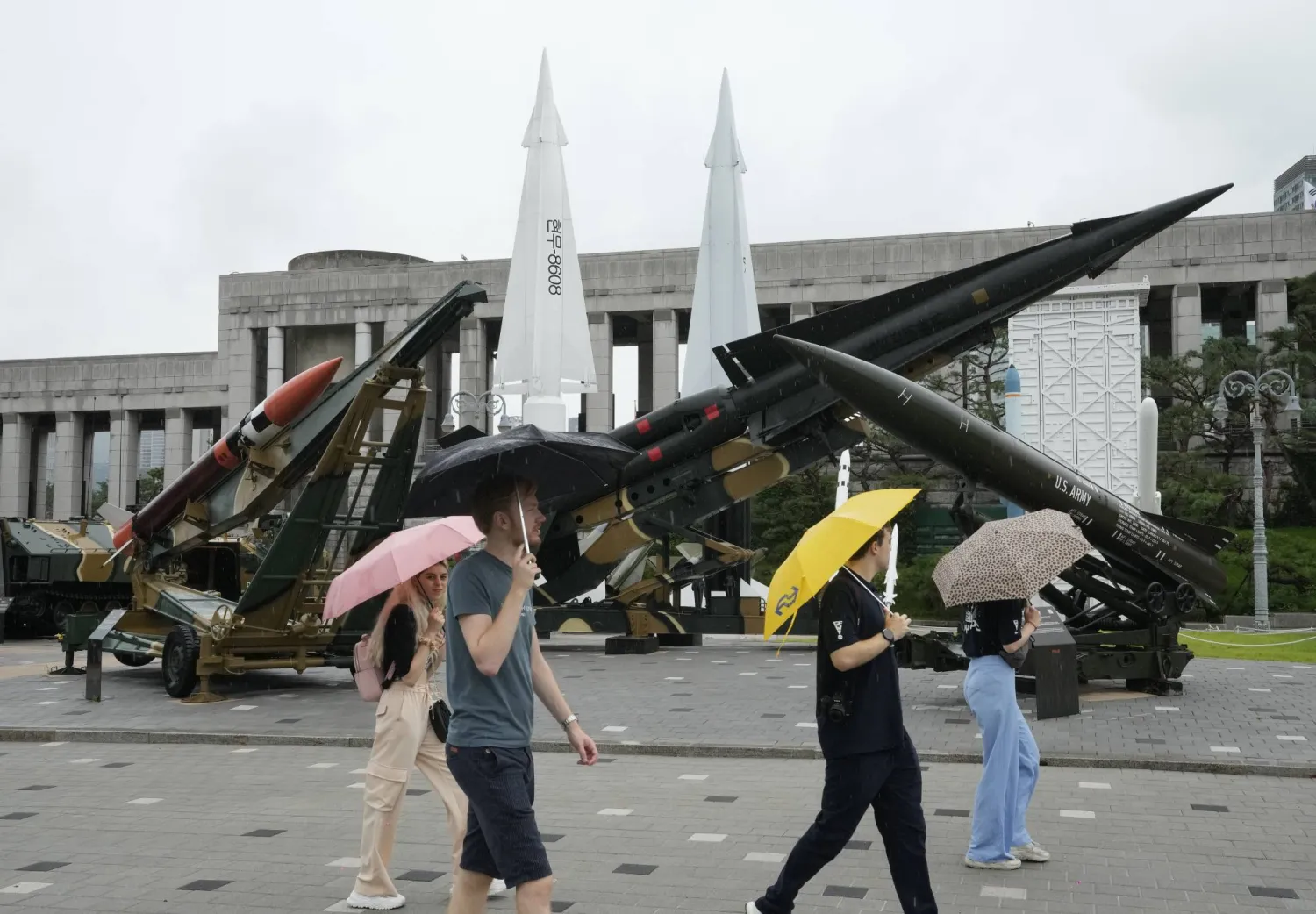 كوريون جنوبيون يمرون قرب متحف حرب كوريا التذكاري في سيول الثلاثاء (أ.ب)