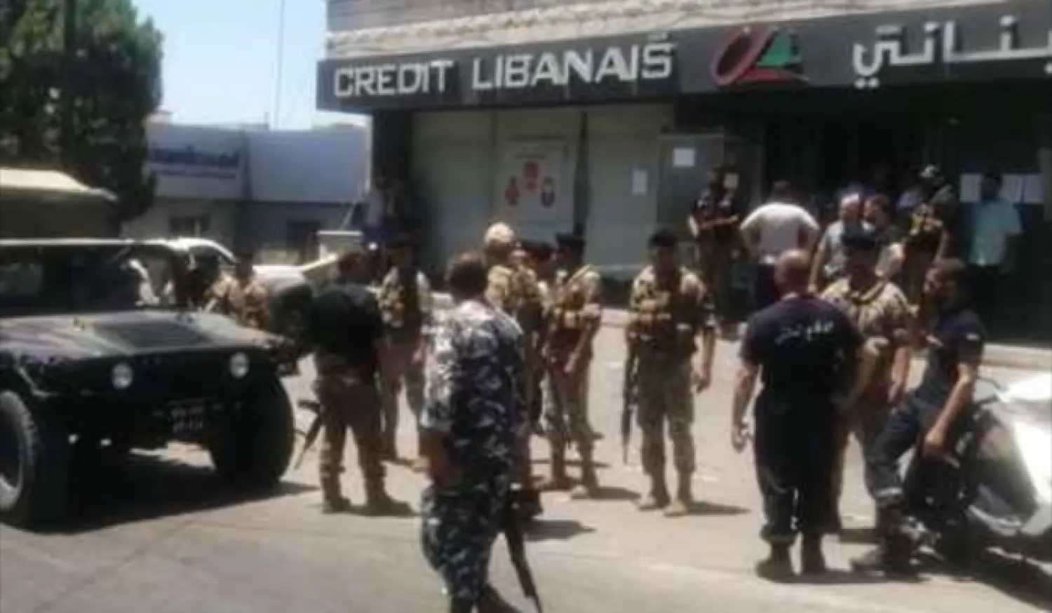 رجال أمن ومواطنون أمام فرع أحد المصارف الذي تعرض للاقتحام (الوكالة الوطنية)