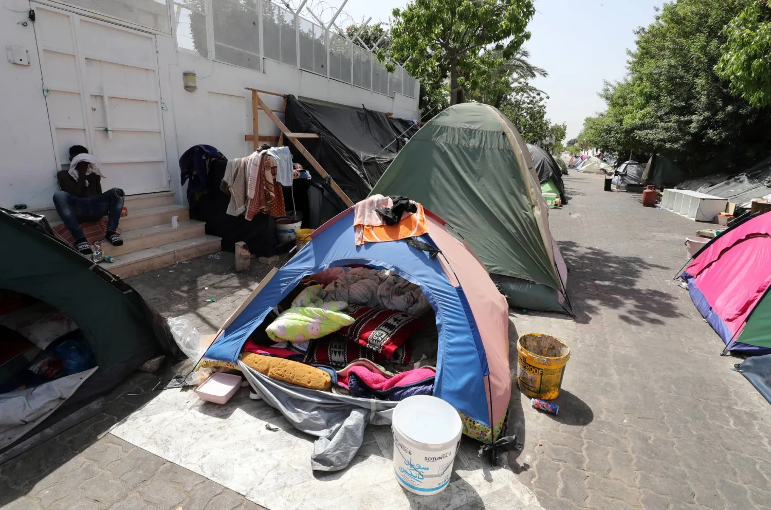 مهاجرون أفارقة أمام مقر مبنى المفوضية الدولية للمهاجرين في تونس للمطالبة بترحيلهم إلى بلد آخر بسبب تزايد الاعتداءات عليهم (إ.ب.أ)