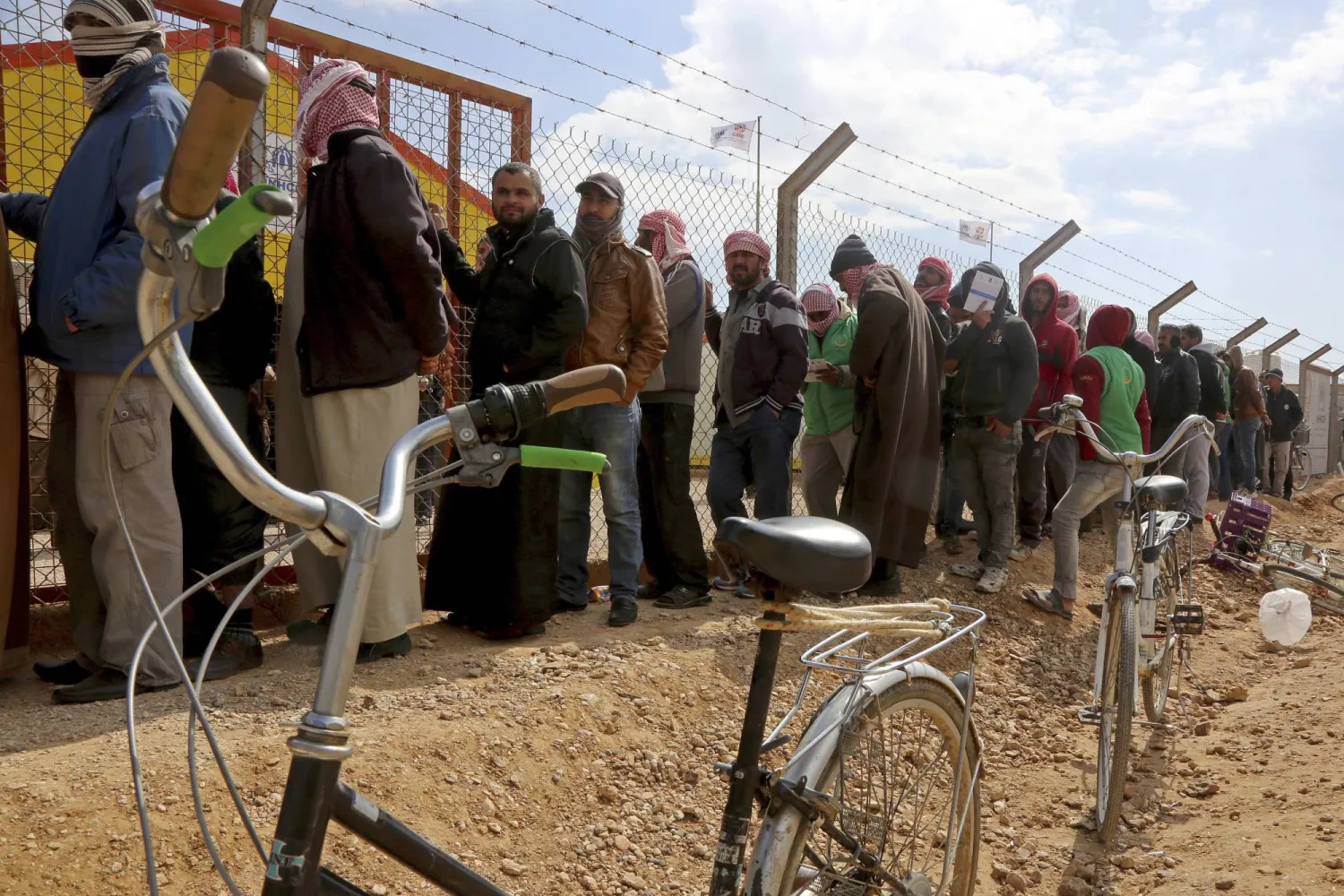 FILE - Syrian refugees line up to register their names at an employment office, Feb. 18, 2018, at the Azraq Refugee Camp, 100 kilometers east of Amman, Jordan. (AP Photo/Raad Adayleh, File)