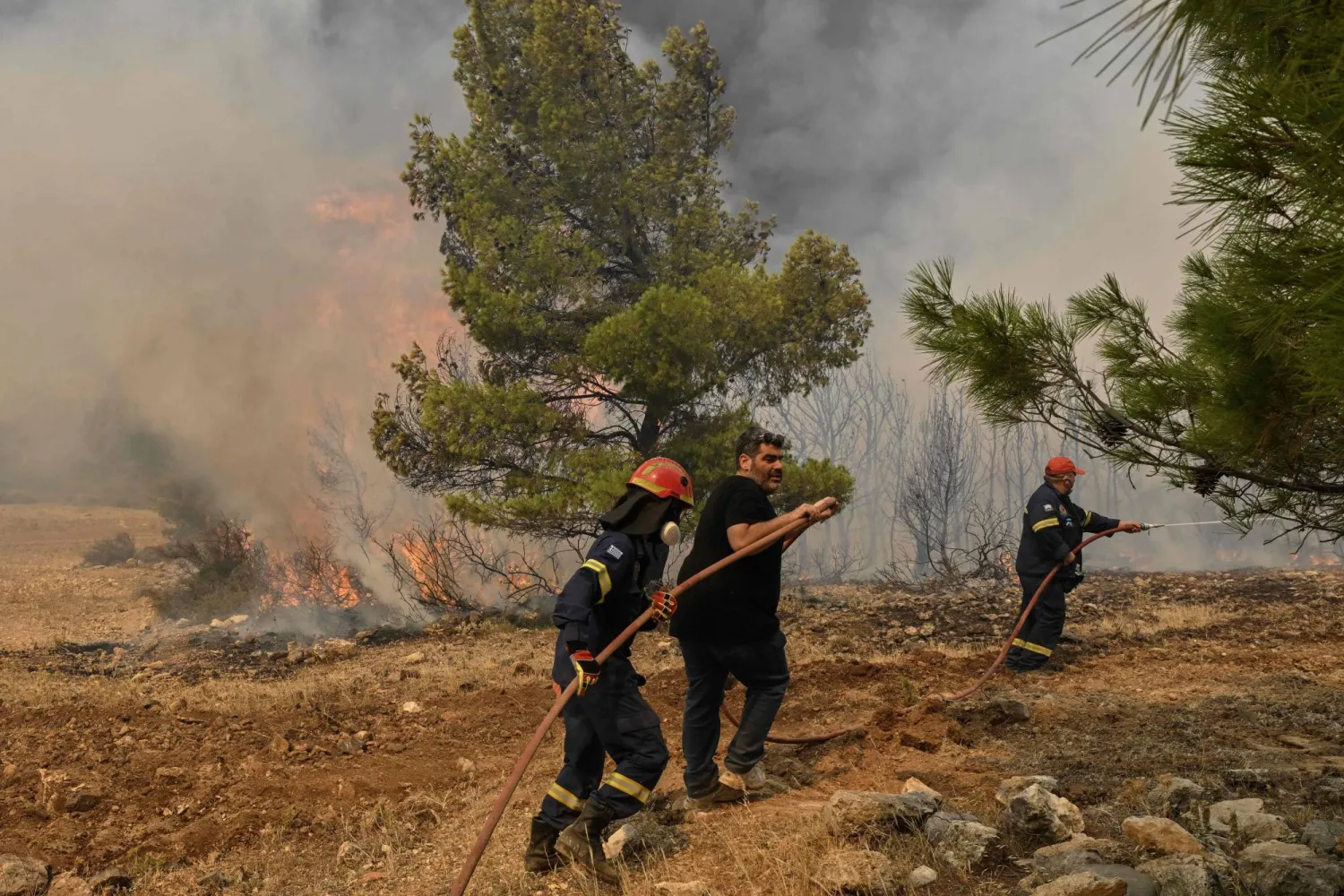 رجال إطفاء خلال محاولتهم إخماد حريق غرب العاصمة أثينا (أ.ف.ب)