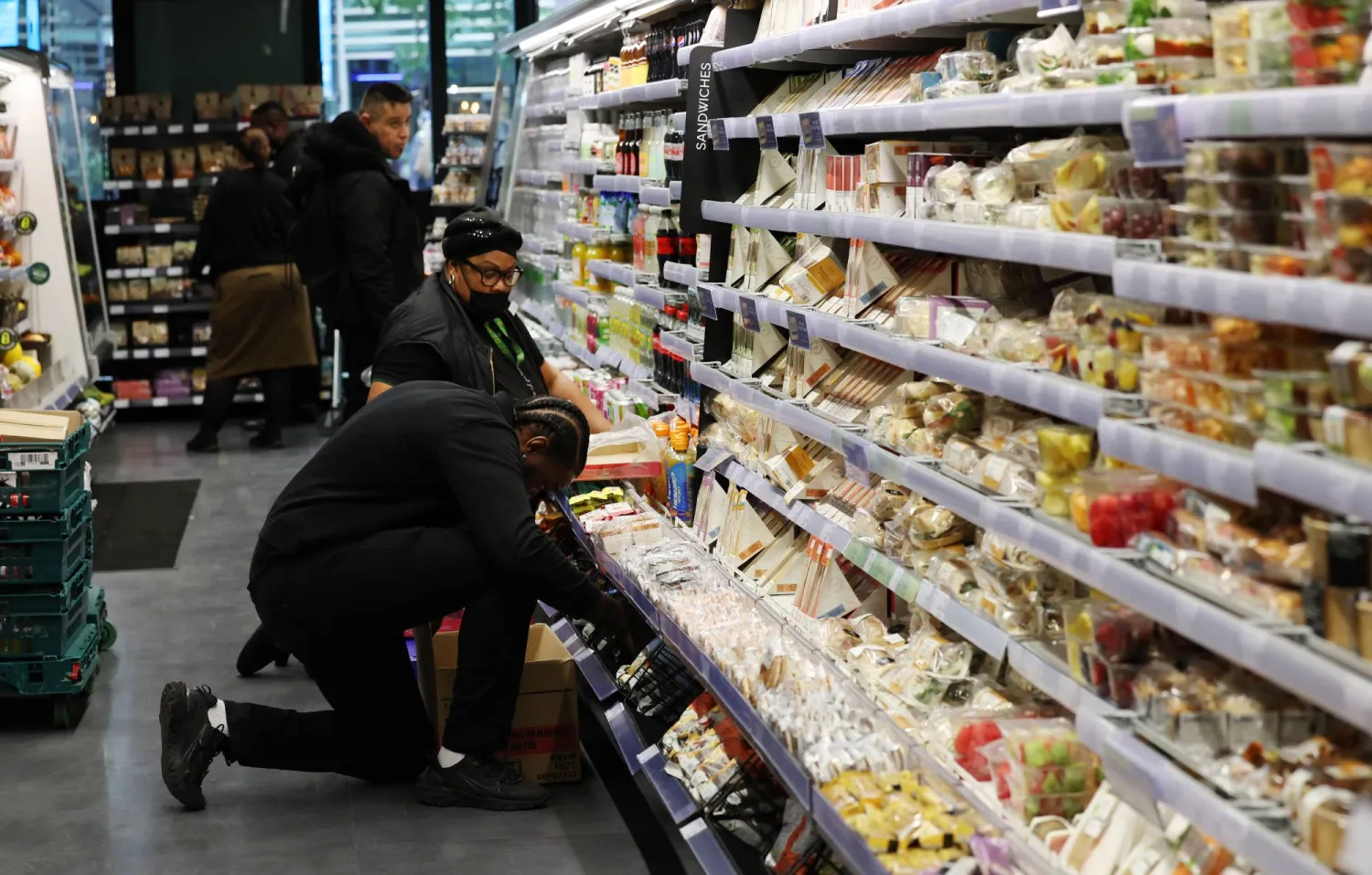 عاملون يقومون برص الببضائع داخل أحد المتاجر الكبرى في العاصمة البريطانية لندن.. بينما أظهرت نتائج التضخم تباطؤا أكثر من المتوقع (إ ب أ) 