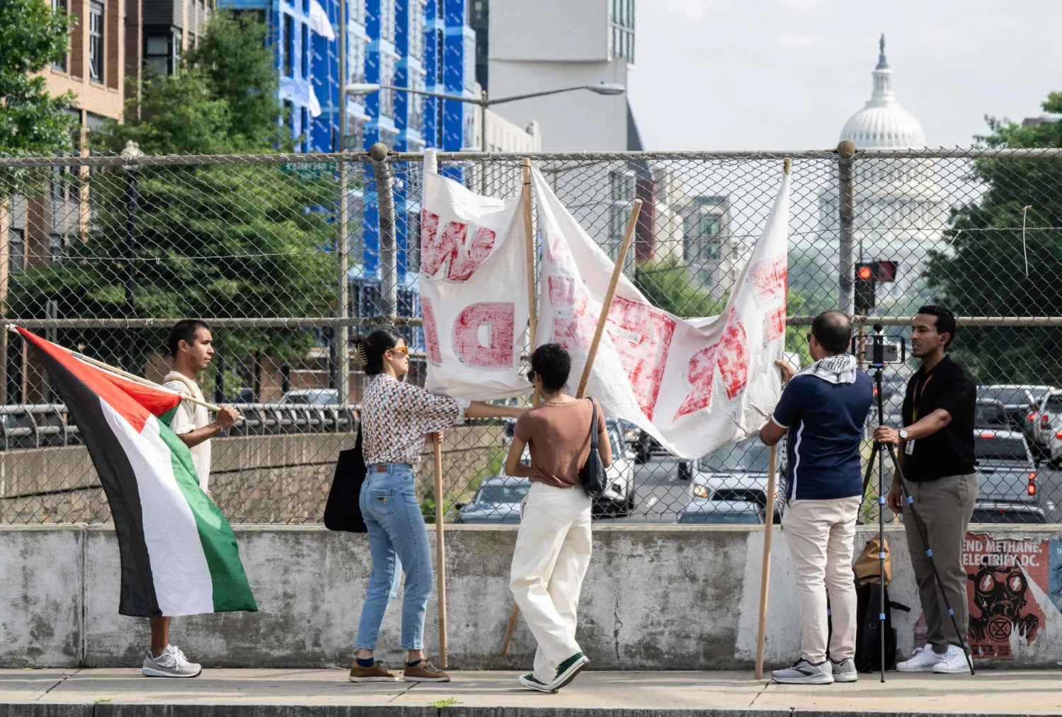 فلسطينيون يرفعون لافتة بالقرب من مبنى الكابيتول الأمريكي في واشنطن العاصمة 19 يوليو احتجاجاً على زيارة الرئيس الإسرائيلي (أ.ف.ب)