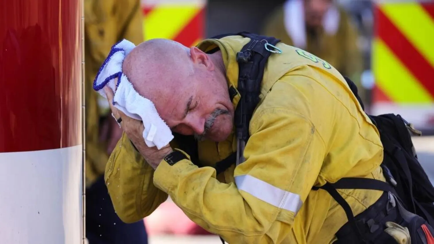 A San Bernardino County firefighter wipes his head as the Oak Fire burns near Fontana, California. DAVID SWANSON / AFP