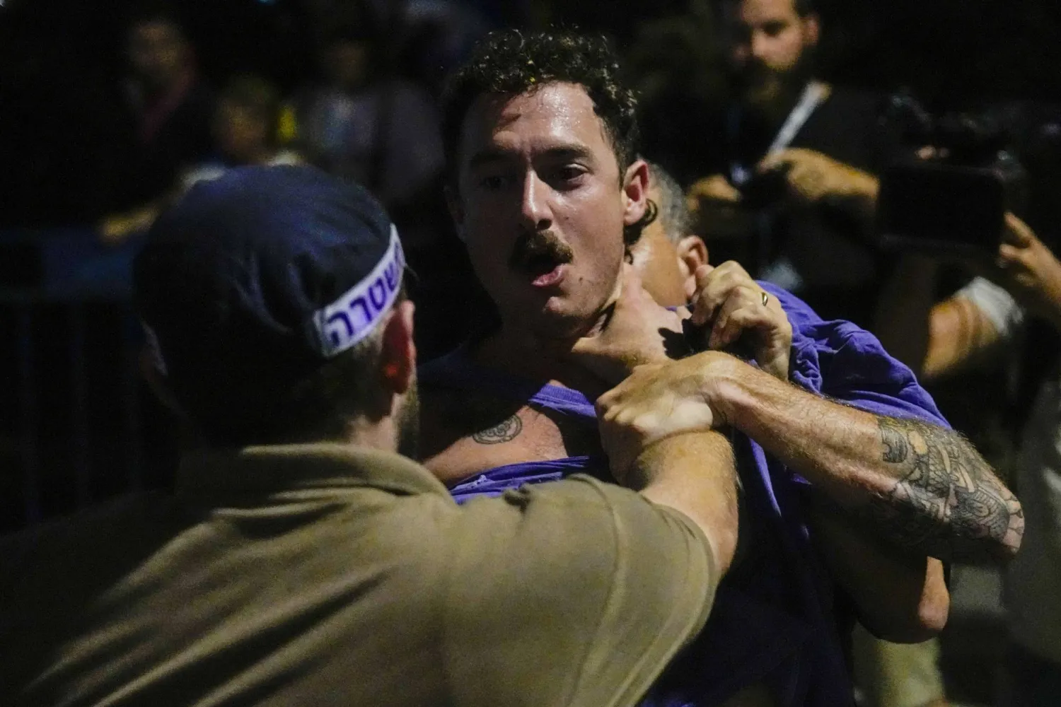 شرطي إسرائيلي يمسك متظاهراً خلال احتجاج ضد حكومة نتنياهو بتل أبيب الخميس (أ.ب)