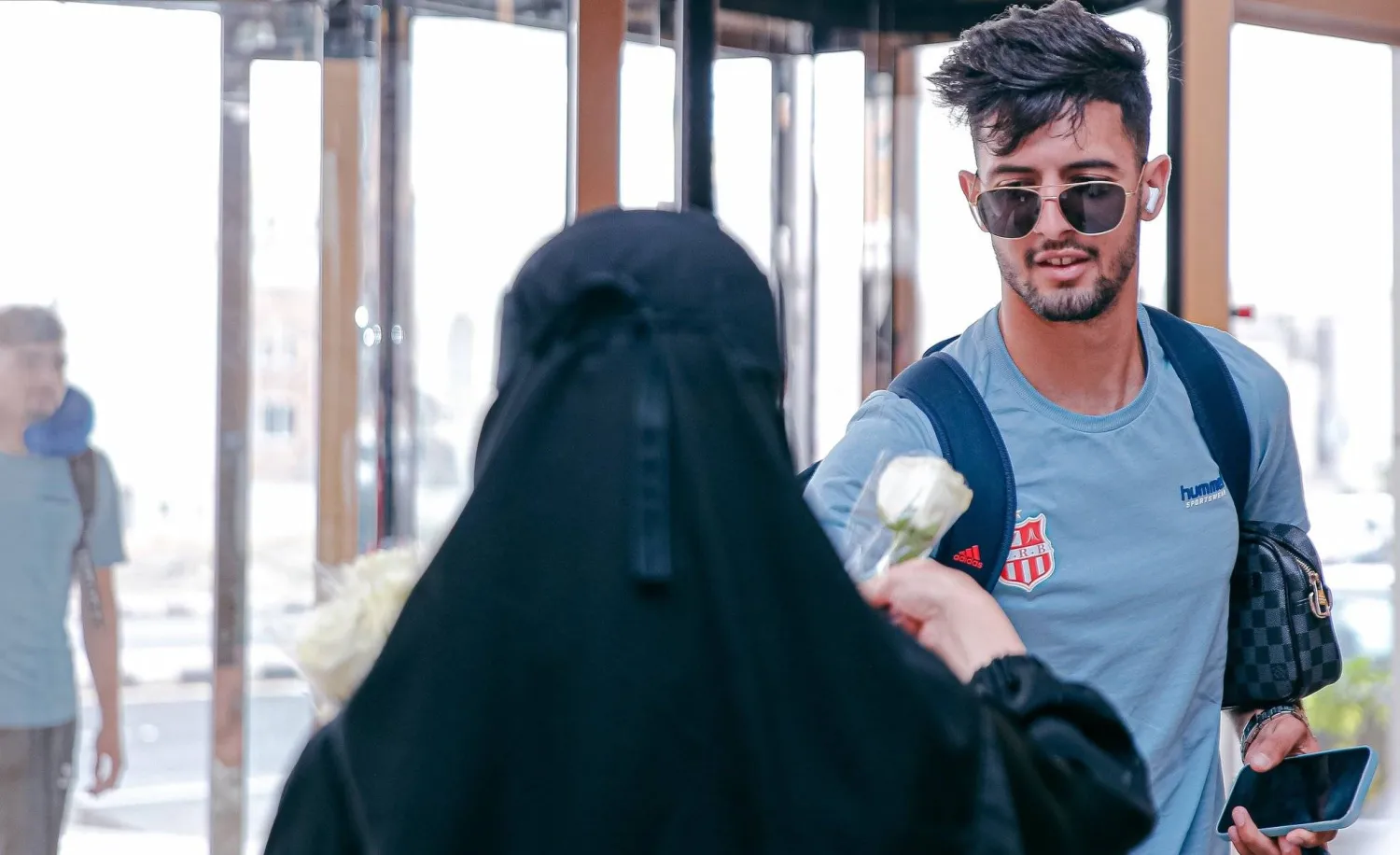 فتاة تقدم وردة لأحد لاعبي بلوزداد الجزائري لدى وصوله إلى أبها (الشرق الأوسط)