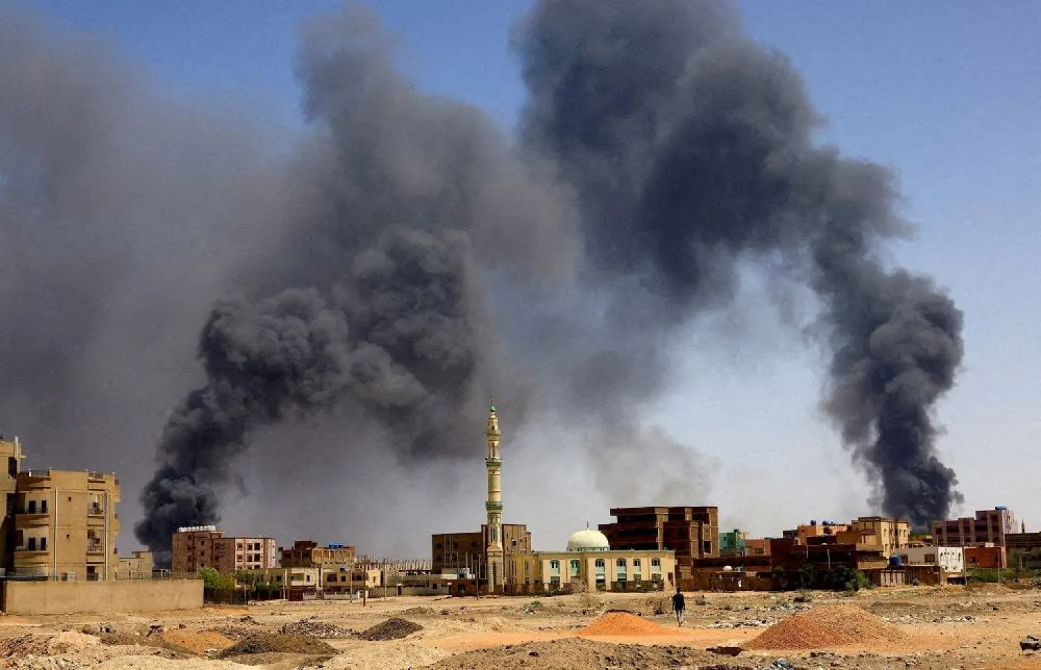 A man walks while smoke rises above buildings after aerial bombardments during clashes between the paramilitary Rapid Support Forces and the army in Khartoum North, Sudan, May 1, 2023. (Reuters)