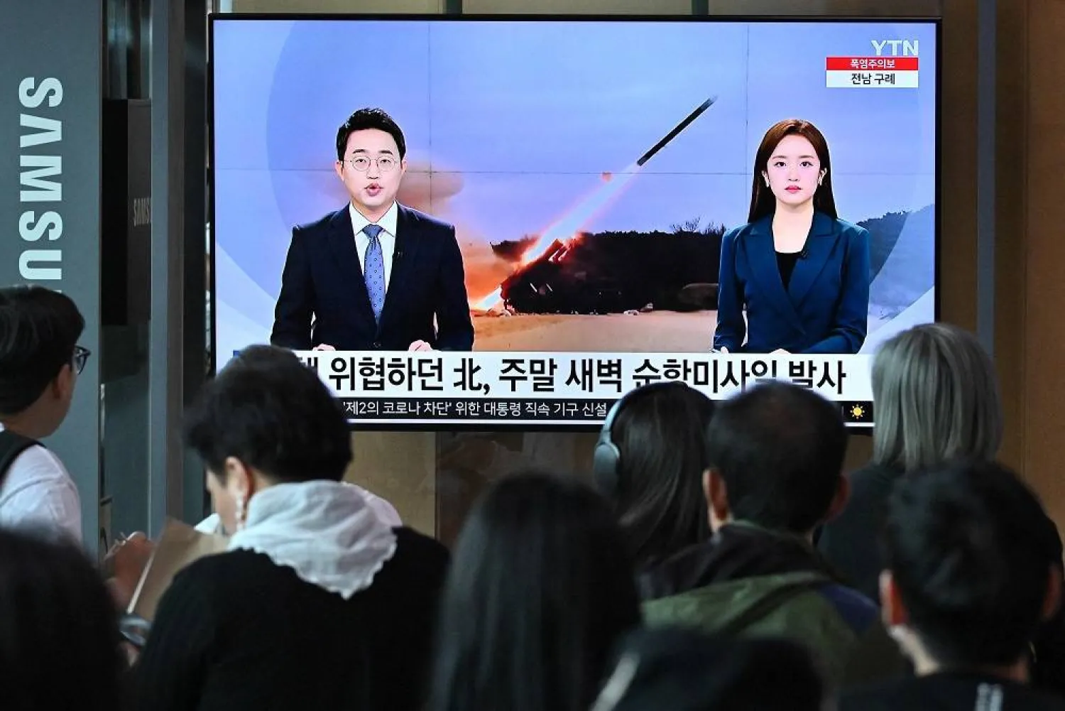 People watch a television screen showing a news broadcast with file footage of a North Korean missile test, at a railway station in Seoul on July 22, 2023. (AFP)