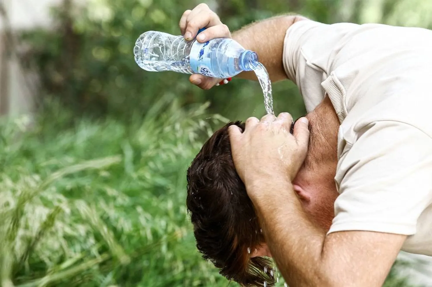 A man pours water on his head to cool off in Algiers on July 18, 2023 during a heatwave. (AFP) 