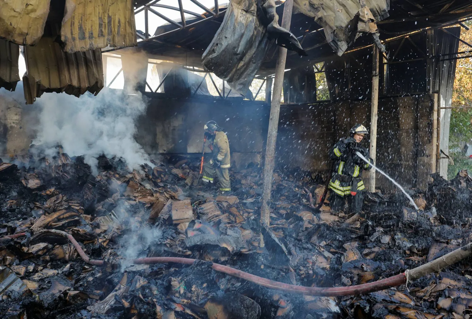 رجال الإطفاء يحاولون إخماد حريق في مستودع دمره قصف روسي على دونيتسك (رويترز)