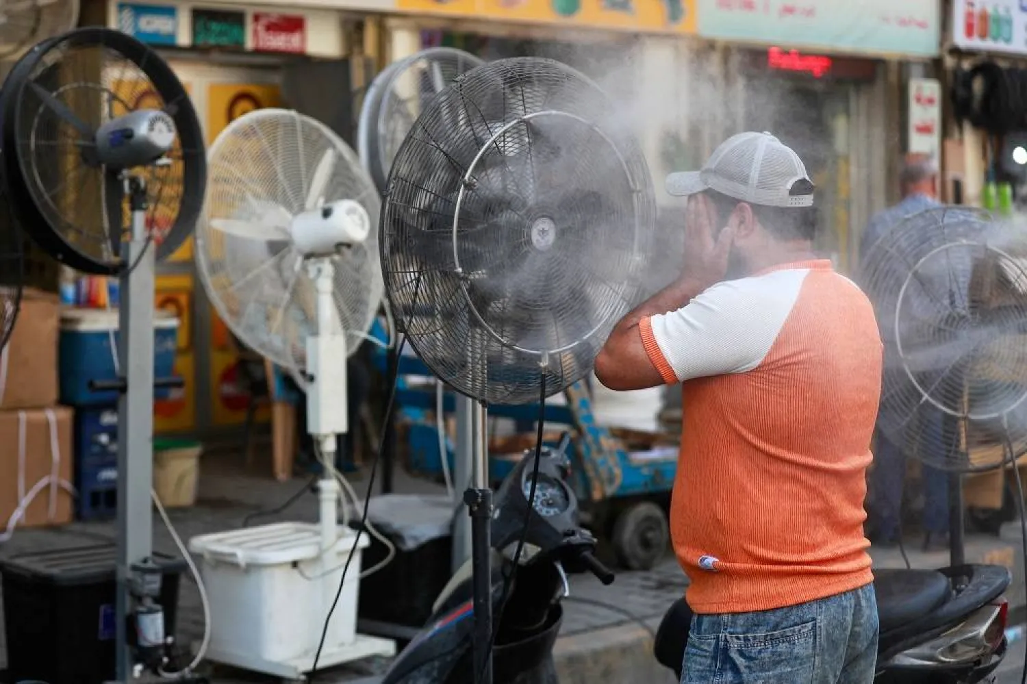 A man cools off with a mist dispenser set up on al-Jumhuriya street in central Baghdad amid soaring temperatures, on July 23, 2023. (AFP)