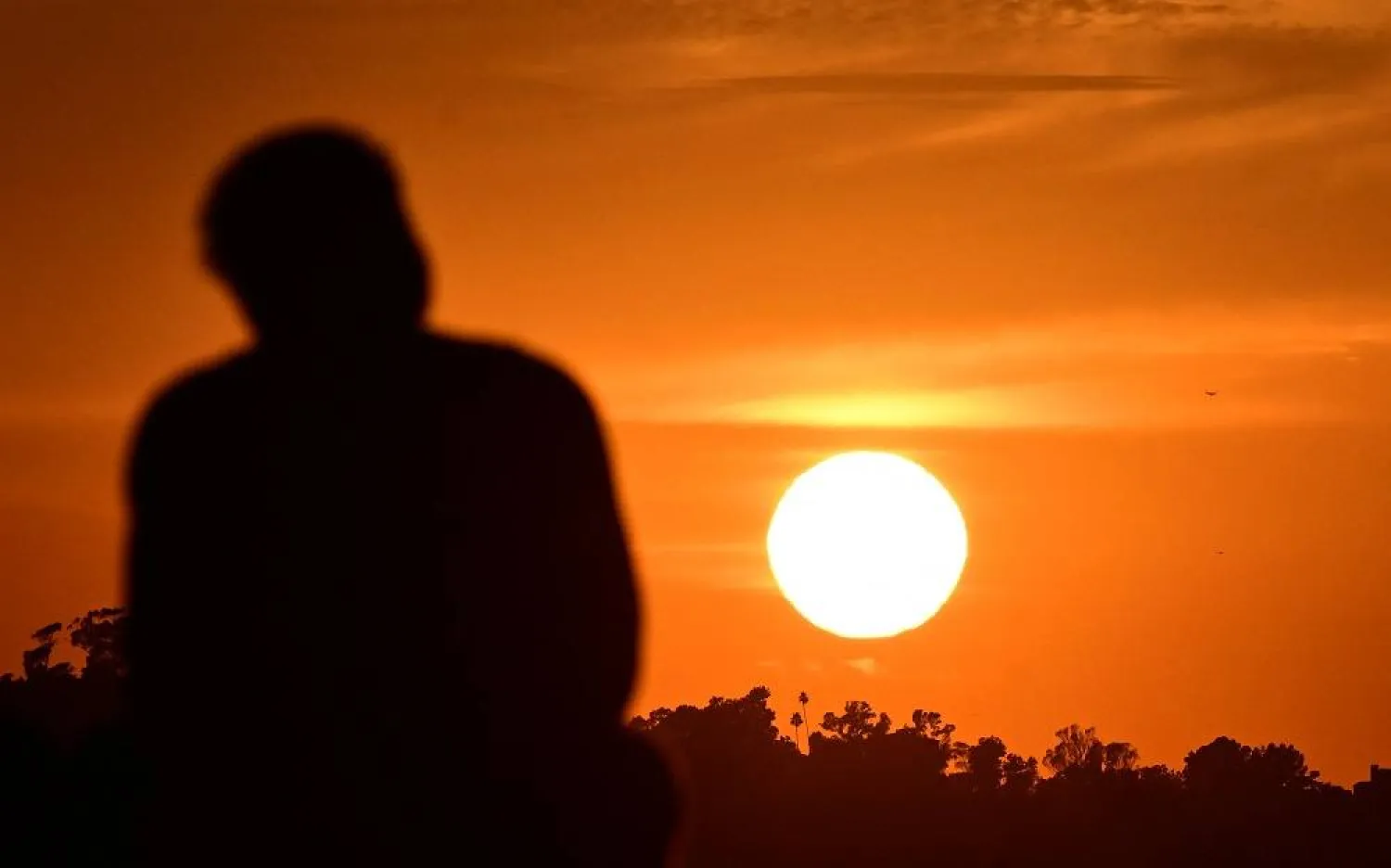 A man watches the setting sun in Los Angeles, California, on July 24, 2023. (AFP)