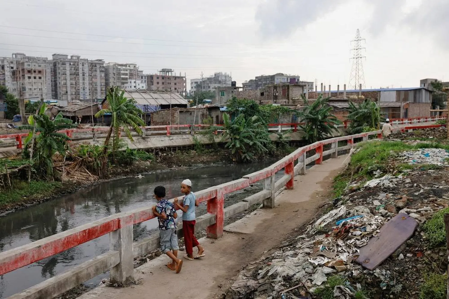 Children look on as they stand on a walkway beside a canal that carries wastewater from tanneries at the Hazaribagh area in Dhaka, Bangladesh, July 9, 2023. (Reuters)