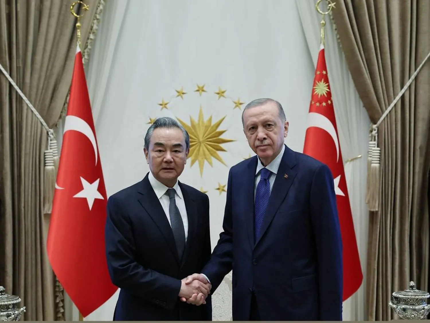 This handout photograph taken and released by the Turkish Presidency Press Office on July 26, 2023, shows Turkish President Recep Tayyip Erdogan shaking hands with Chinese Foreign Minister, Wang Yi (L) at the Presidential Complex in Ankara. (Turkish Presidency Press Office / AFP)  