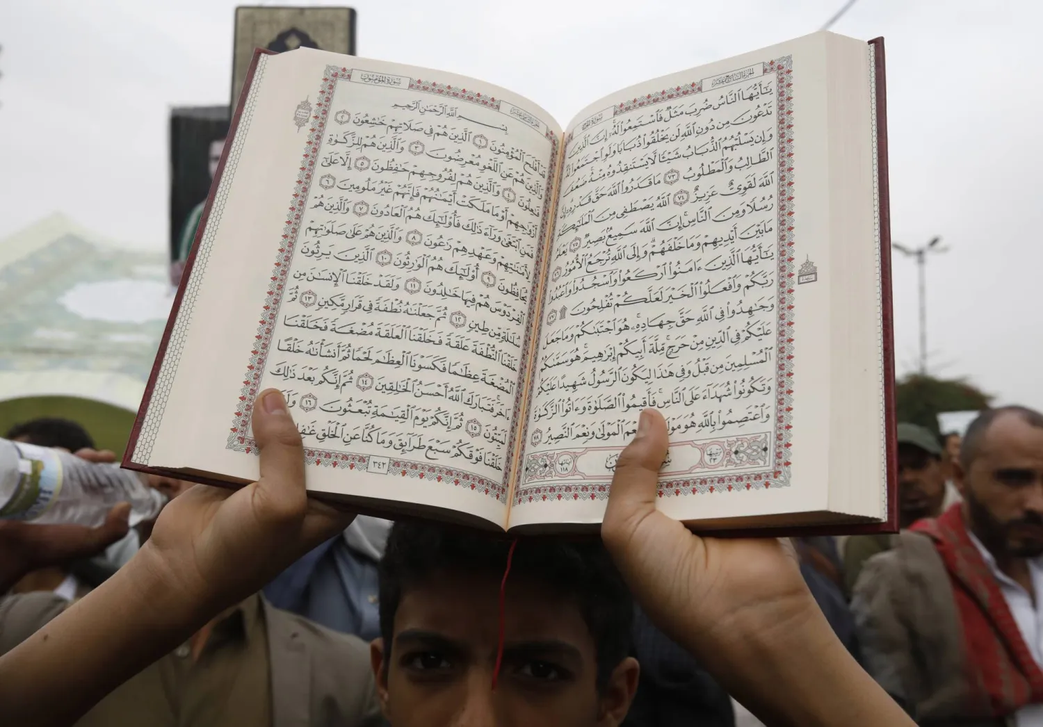 يمني يحمل نسخة من المصحف الشريف خلال احتجاجات في صنعاء ضد حرق المصحف الشريف (إ.ب.أ)