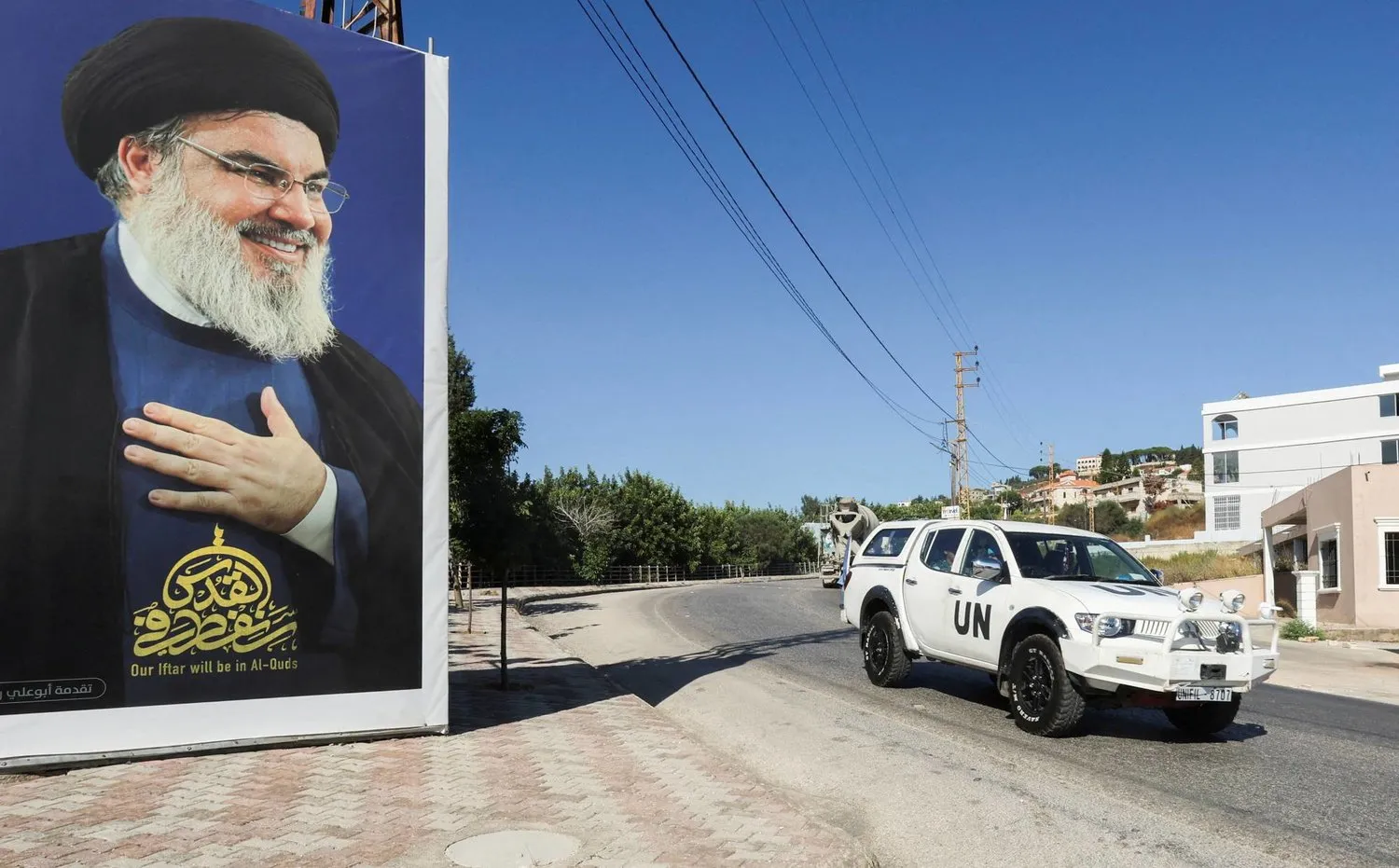 Lübnan-İsrail sınırı yakınlarında Lübnan’ın el-Adise köyünde Hizbullah Örgütü Lideri Hasan Nasrallah’ın bir posterinin yanından geçen UNIFIL barış güçlerine ait bir araç, 12 Temmuz 2023 (Reuters)