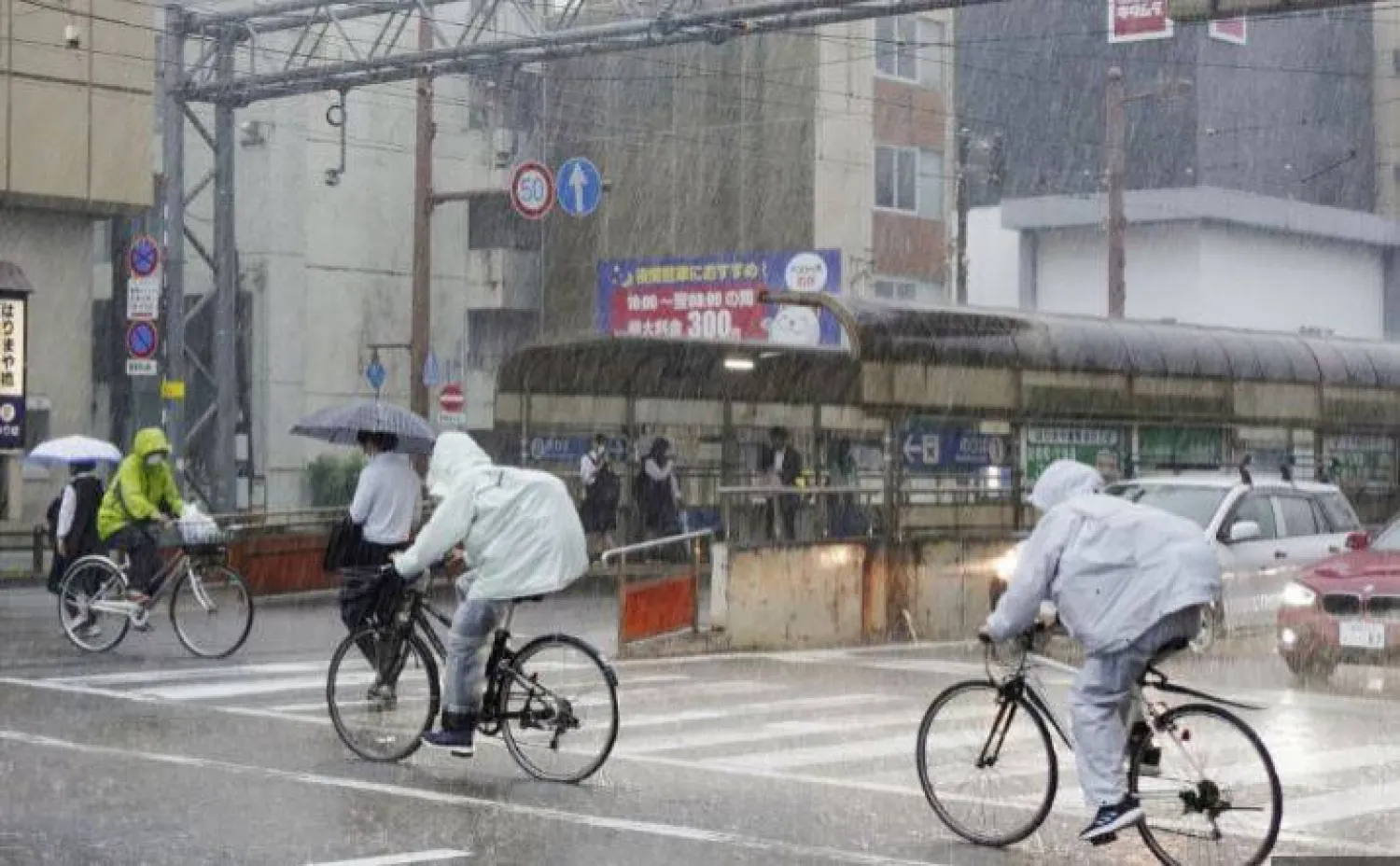 أشخاص يركبون دراجات وسط الأمطار الغزيرة في كوتشي باليابان (أرشيفية - رويترز)