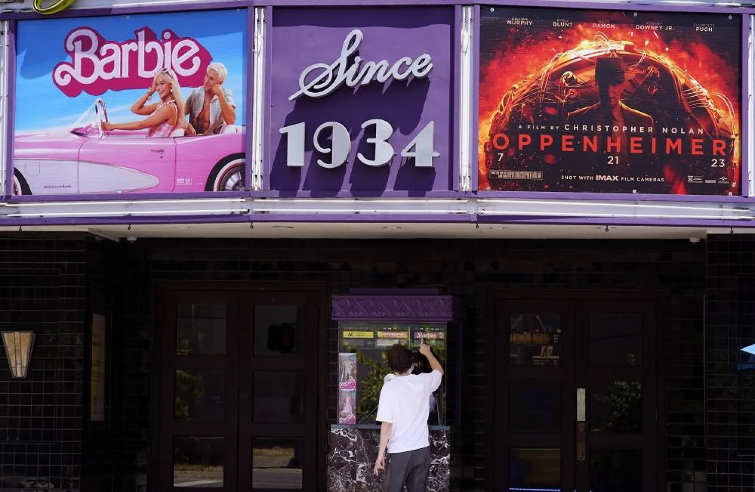A patron buys a movie ticket underneath a marquee featuring the films "Barbie" and "Oppenheimer" at the Los Feliz Theatre, Friday, July 28, 2023, in Los Angeles. (AP)