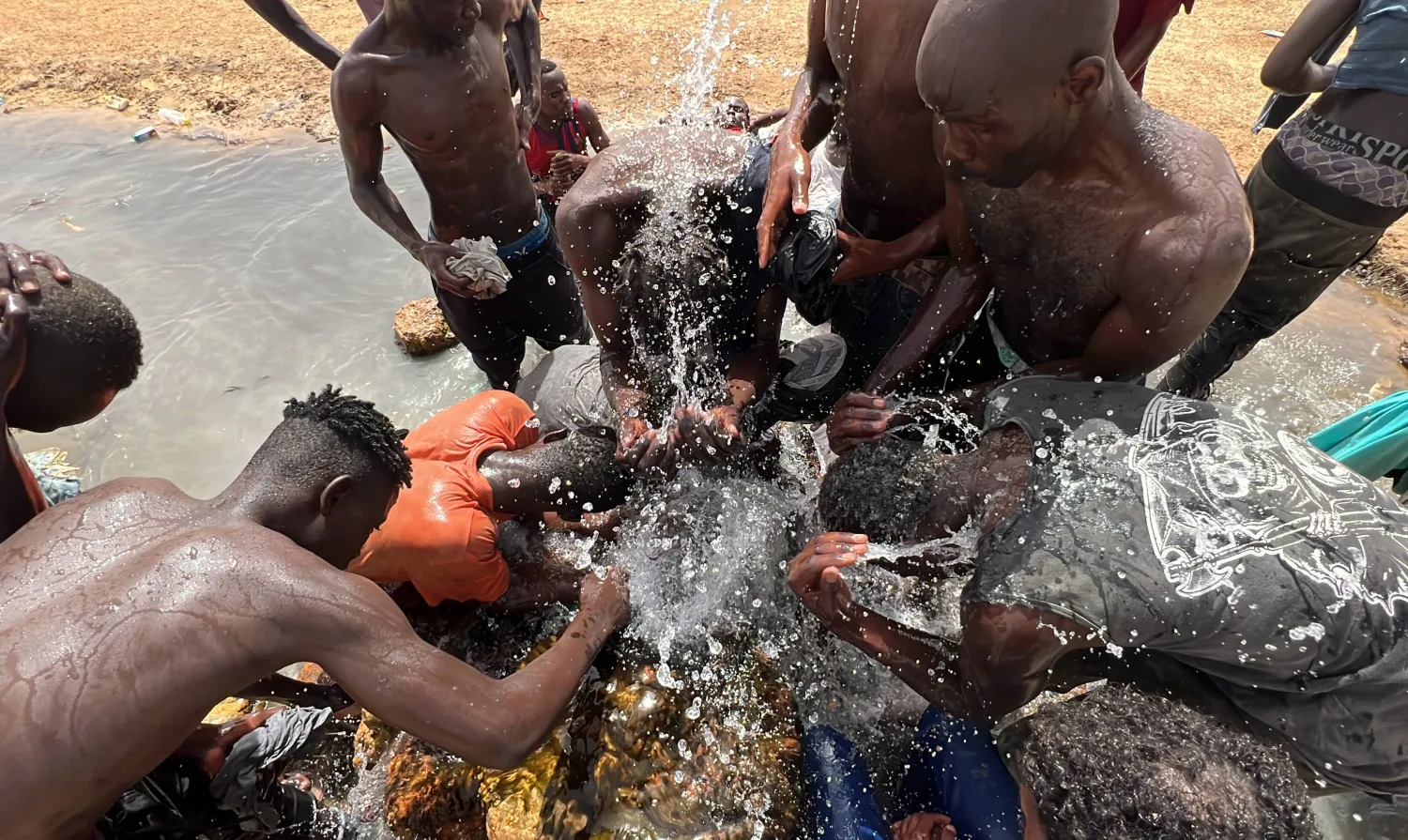 مهاجرون من أفريقيا جنوب الصحراء يغتسلون عند وصولهم إلى منطقة غير مأهولة على الحدود الليبية التونسية بالقرب من العسة (160 كيلومتراً غرب طرابلس بليبيا) في 30 يوليو 2023 (إ.ب.أ)