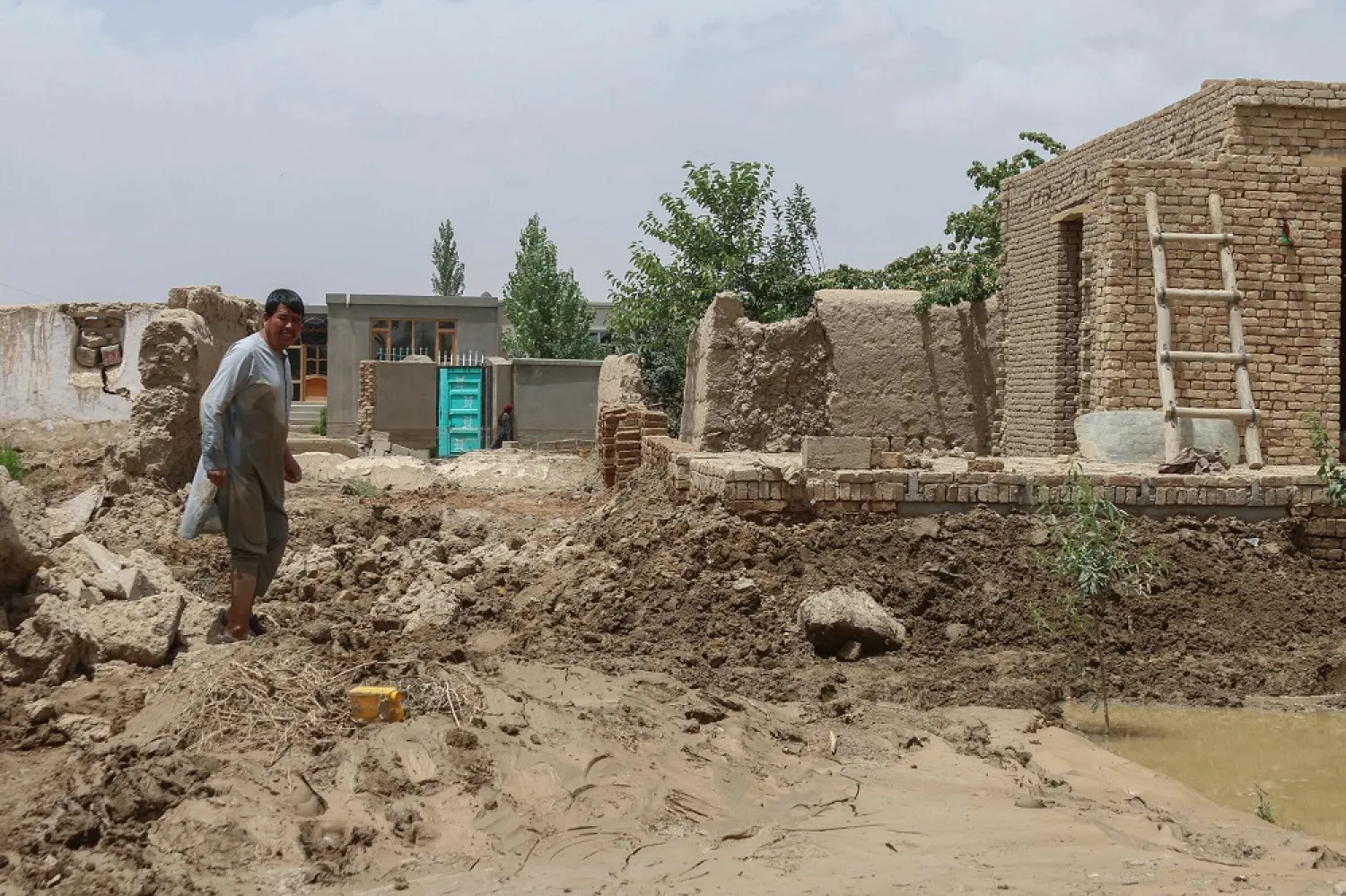 An Afghan man walks through a street covered in mud following flash floods in the Khair Abad area in Ghazni province on July 23, 2023. (AFP) 