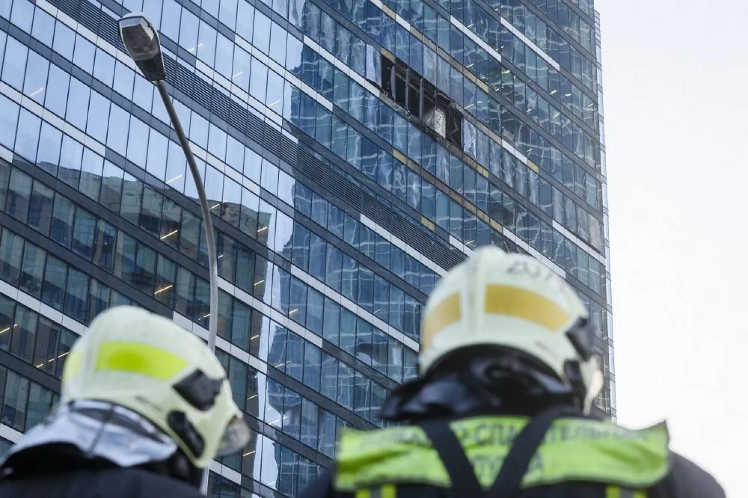 Firefighters stand next to a damaged building in the "Moscow City" business district after a reported drone attack in Moscow, Russia, early Tuesday, Aug. 1, 2023. (AP)
