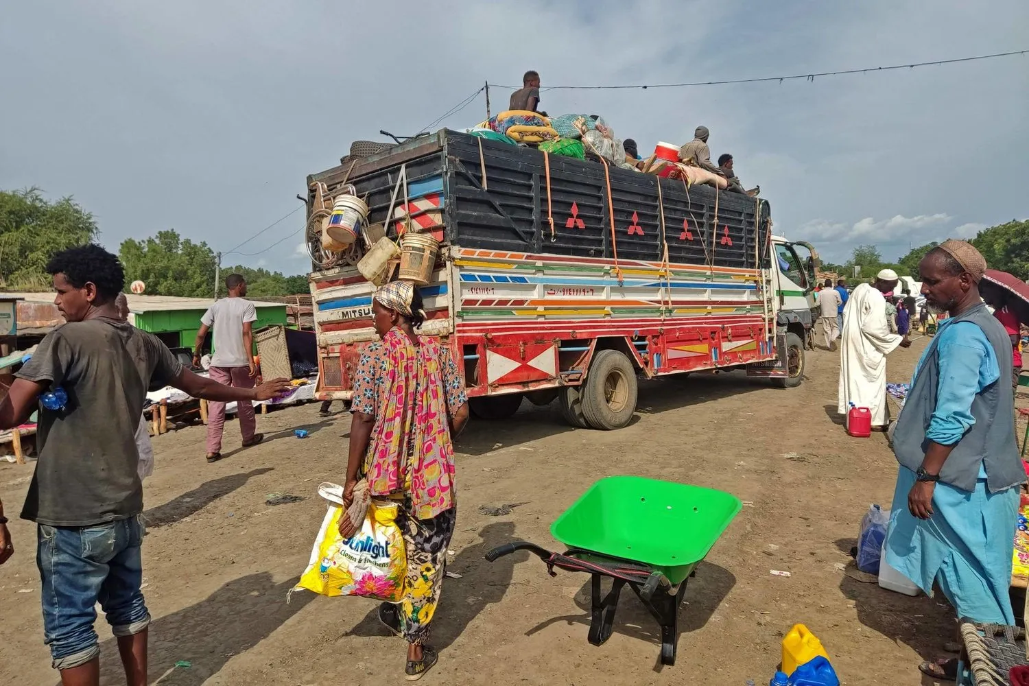 İnsanlar Sudan'ın Etiyopya ile Galabat sınır kapısından otobüse binmek için bekliyor (AFP)