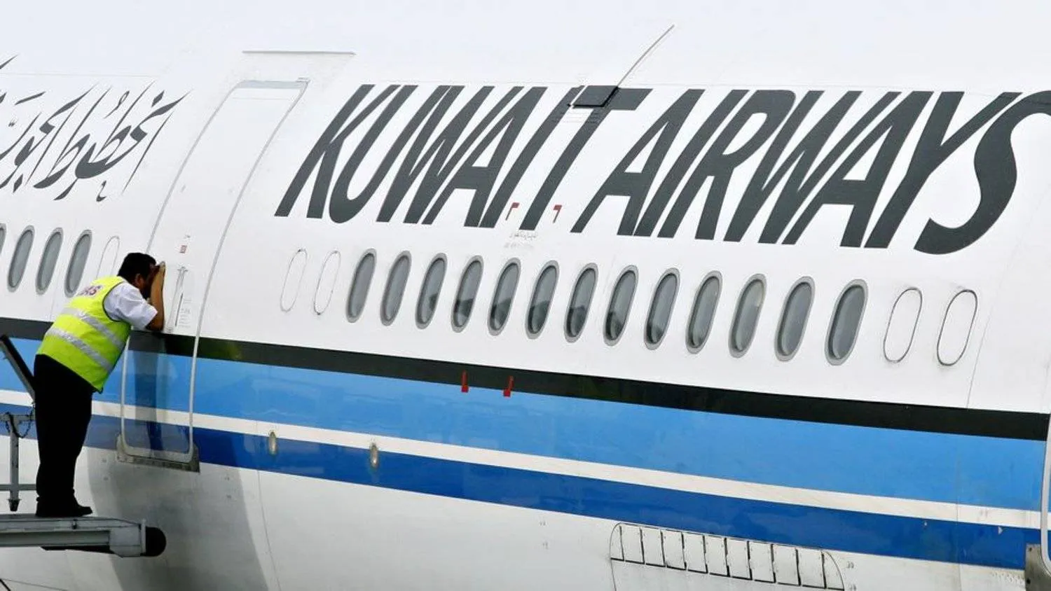 A ground crew member takes a peek inside the cabin of a Kuwait Airways Airbus A340. AFP file photo
