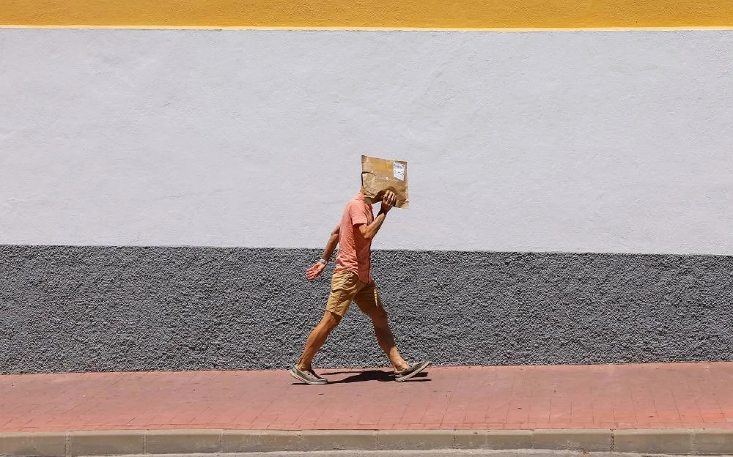 A man uses a package to protect his head from the strong sun as he walks along a street during a hot summer day in Ronda, Spain, August 2, 2023. (Reuters)