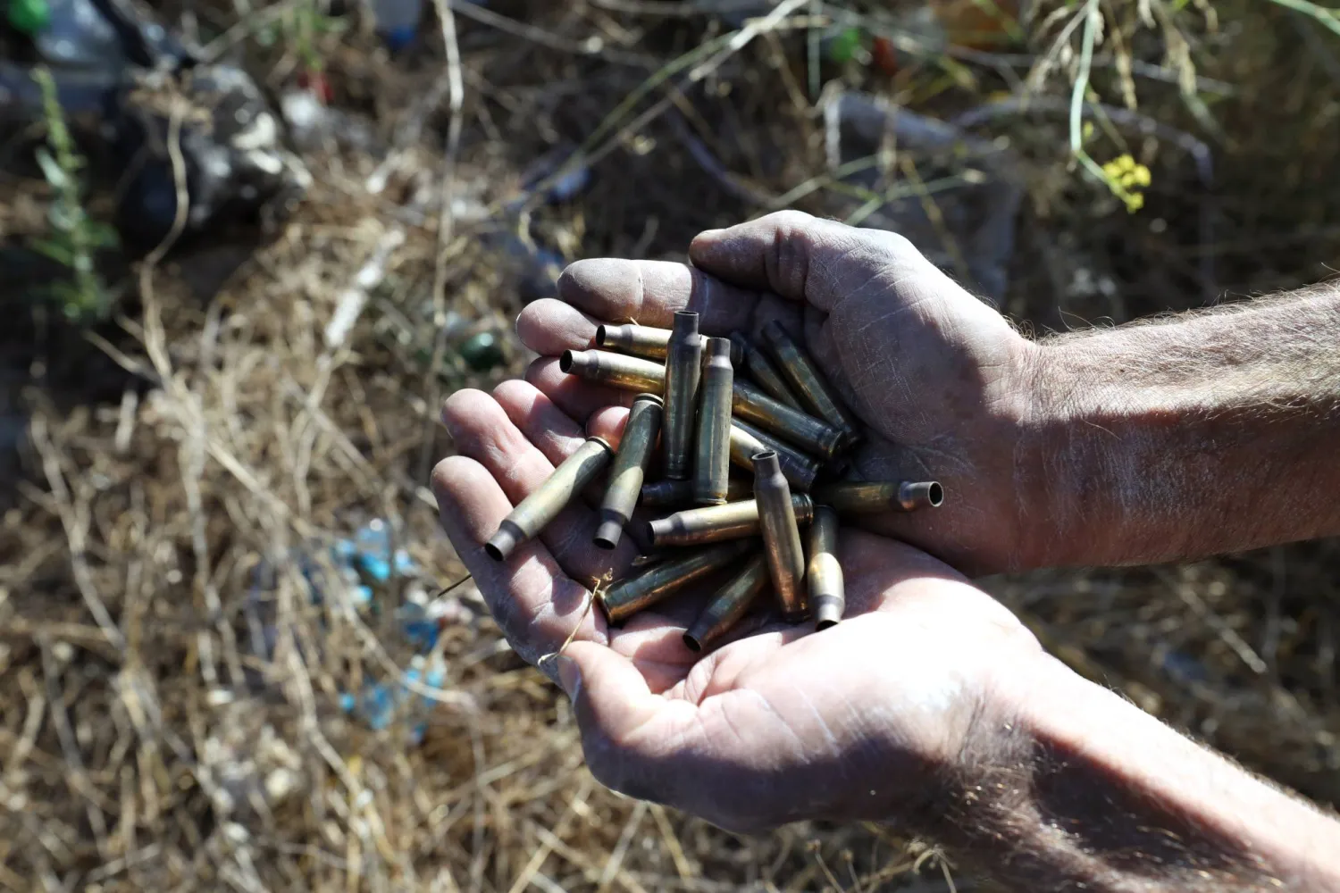 رجل يحمل مجموعة من فوارغ الرصاصات في مكان شهد مقتل 3 فلسطينيين على يد قوة إسرائيلية قرب جنين (إ.ب.أ)