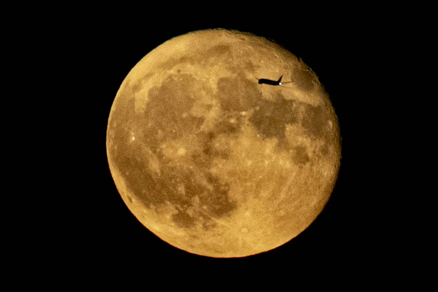 A jetliner flying from JFK is silhouetted against the moon, Wednesday, Aug. 2, 2023, in New York. (AP Photo/Bebeto Matthews)