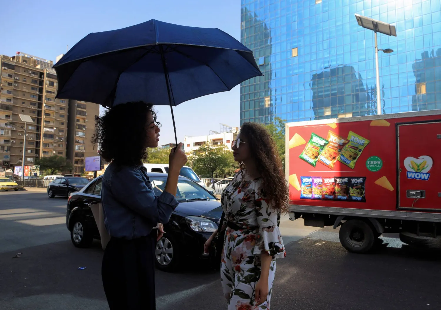 يحتمين من شمس دمشق الحارقة بمظلة (رويترز)