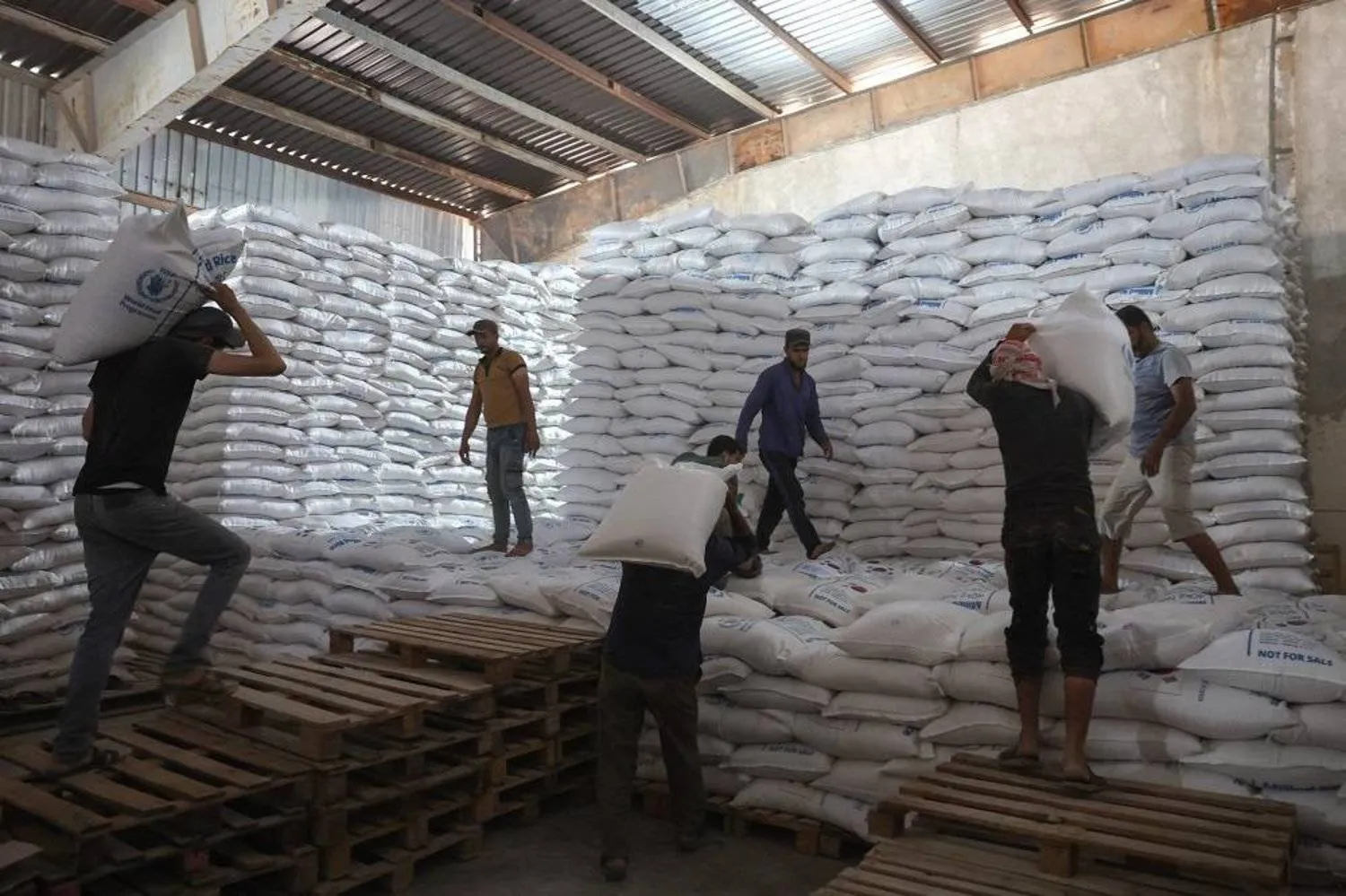 Workers unload bags of aid at a warehouse near the Syrian Bab al-Hawa border crossing with Türkiye , on July 10, 2023. (AFP)
