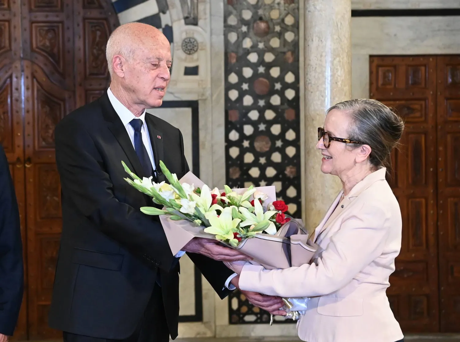 epa10782071 A  handout photo made available by the Tunisian Presidency's official shows Tunisian President Kais Saied offering flowers to outgoing Prime Minister Najla Bouden during a handover ceremony at the Kasbah Palace in Tunis, Tunisia on 02 August 2023. Tunisian President Kaïs Saïed has decided to 'terminate the functions' of Prime Minister Najla Bouden, the first woman to lead a government in Tunisia, on the evening of 01 August . He immediately appointed in her place Ahmed Hachani, who until now worked at the Central Bank of Tunisia and studied at the Faculty of Law of the University of Tunis where Kaïs Saïed taught.  EPA/Tunisian Presidency HANDOUT  HANDOUT EDITORIAL USE ONLY/NO SALES