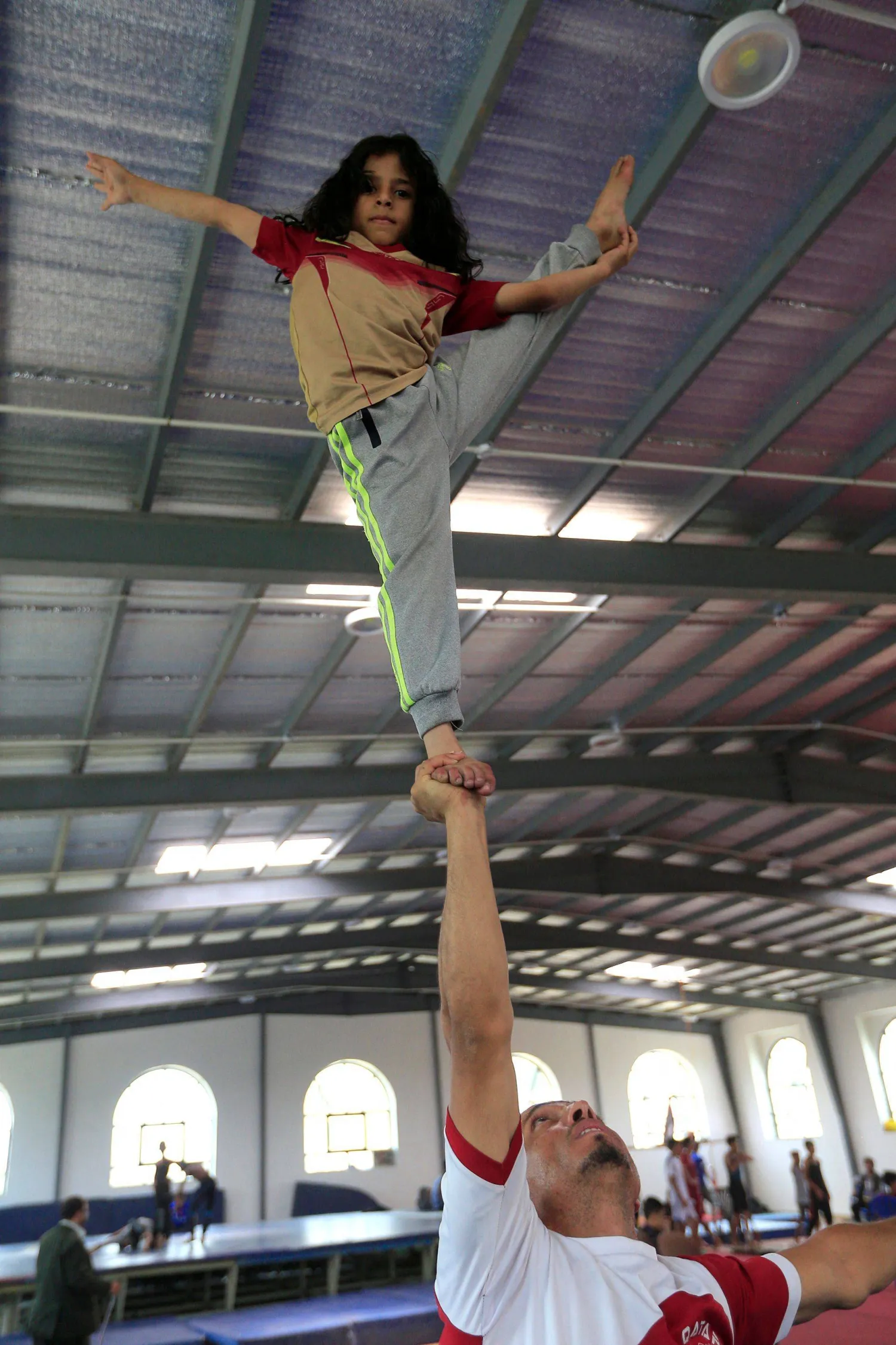 A Yemeni carries his daughter during a local gymnastics championship in Sanaa (AFP)
