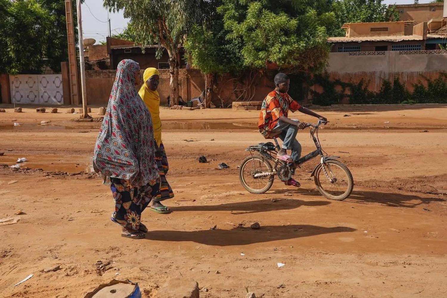  Two women walk as a boy cycles in the streets of Niamey, Niger, Sunday, Aug. 13, 2023. (AP)