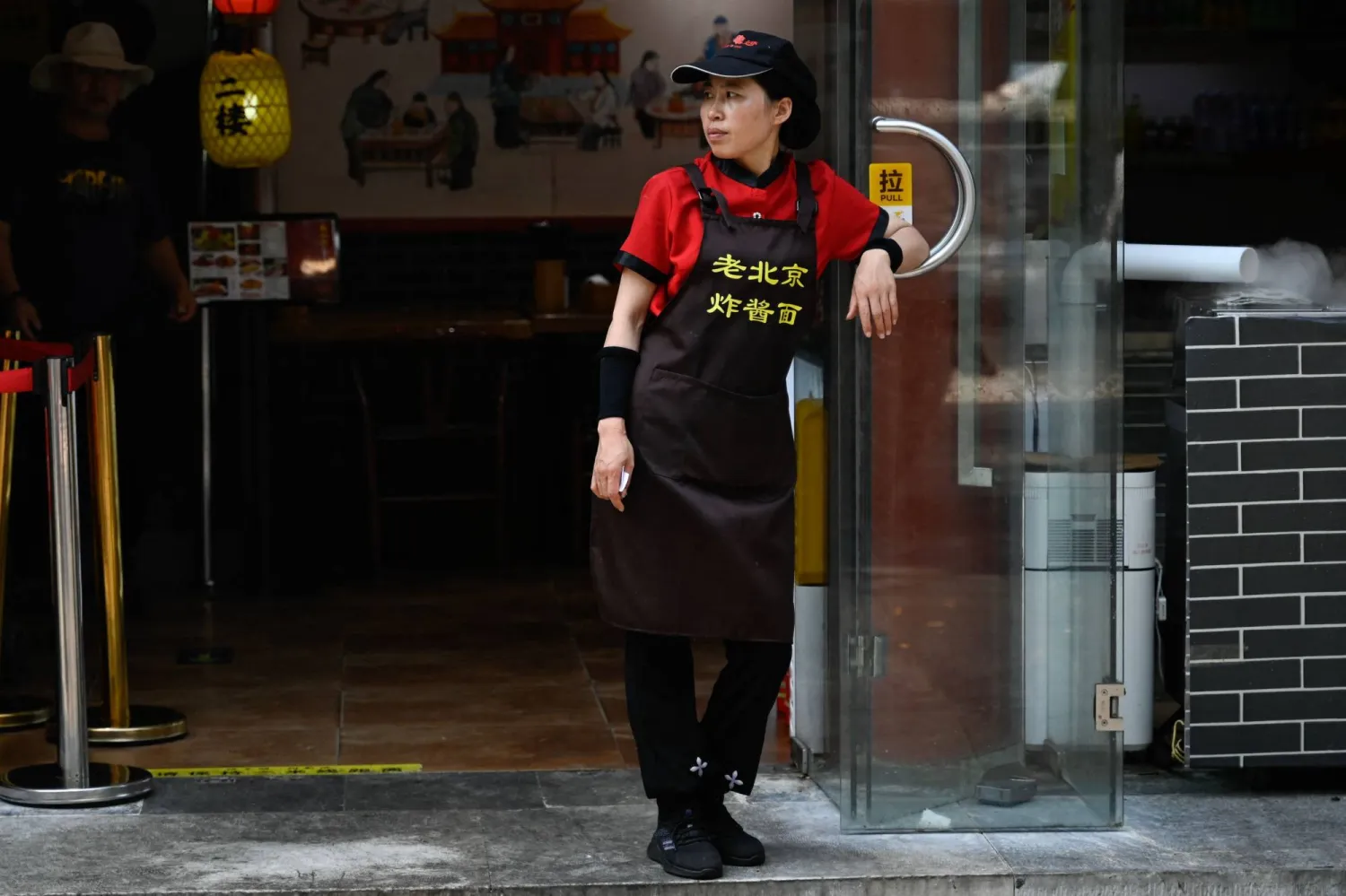 موظف يقف خارج مطعم ببكين في 15 أغسطس 2023 (أ.ف.ب)