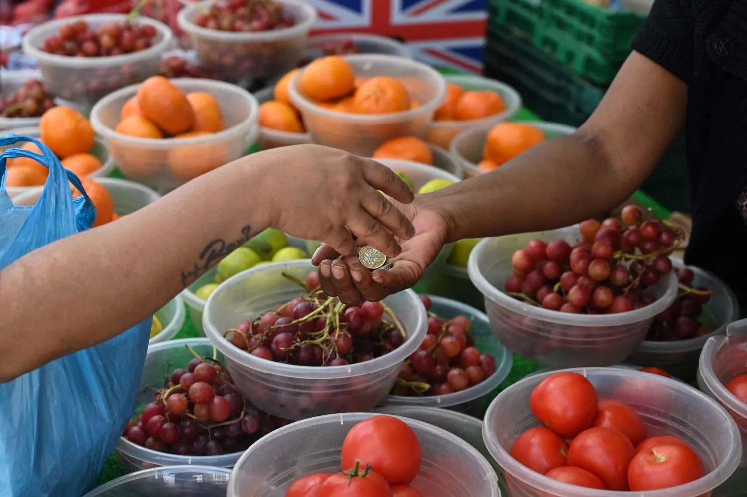 عميل يدفع بعد شراء بعض الفواكه والخضراوات في سوق شارع في هاي ويكومب، في 15 أغسطس 2023 (أ.ف.ب)