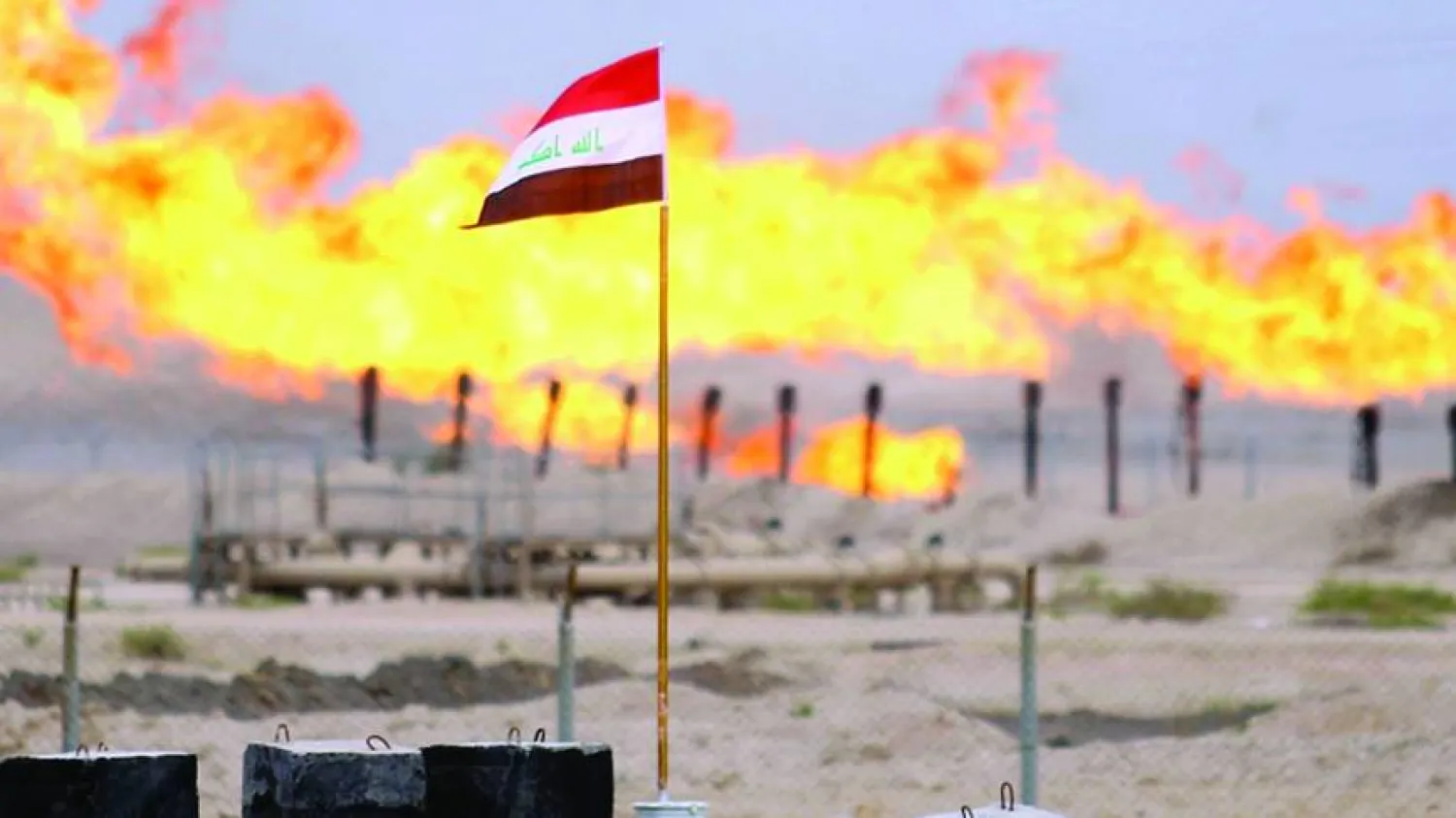 علم العراق يرفرف عند مدخل حقل نفطي (رويترز)