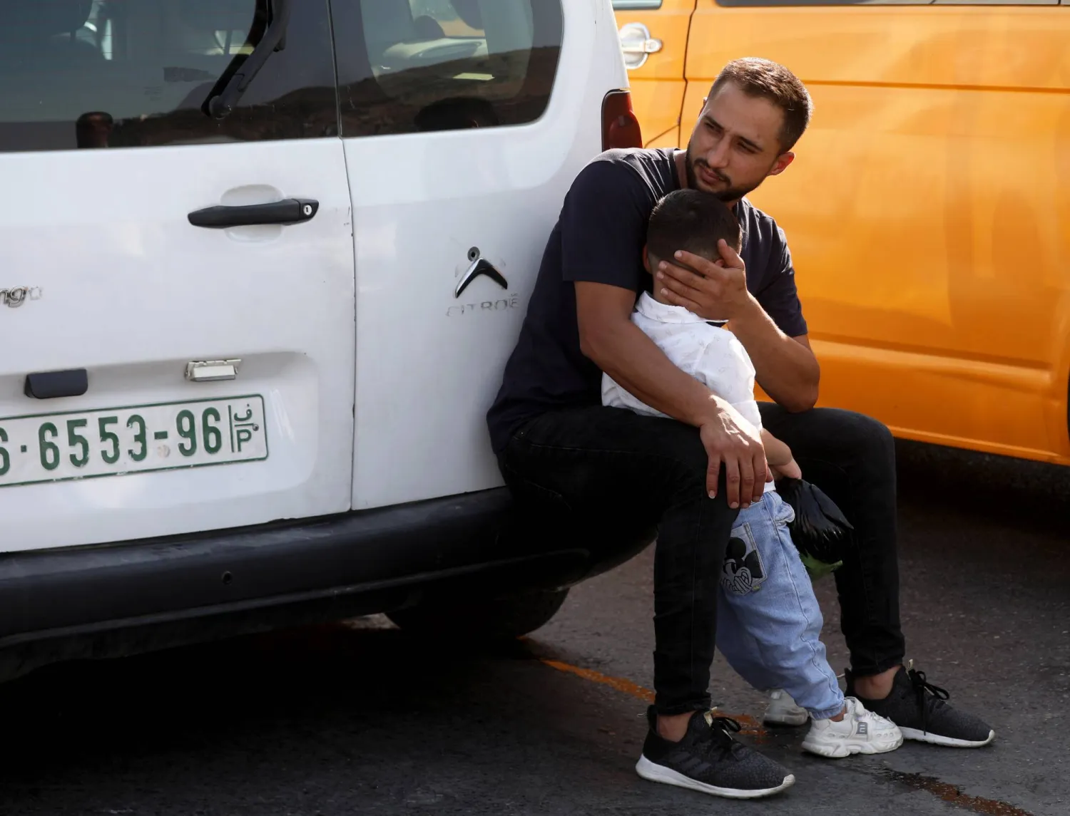 فلسطيني مع طفله ينتظر فتح الطريق عند حاجز حوارة بعد مقتل إسرائيليين اثنين السبت (إ.ب.أ)